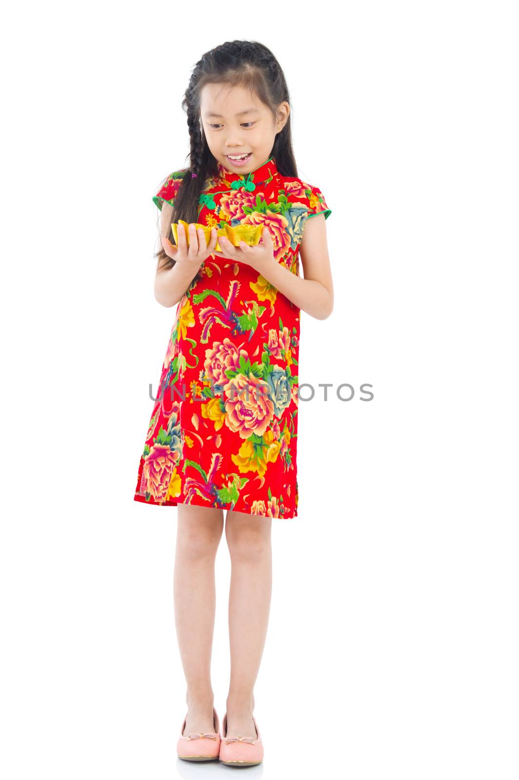 Full length China girl in traditional Chinese cheongsam dress greeting, holding a gold ingot standing isolated on white background