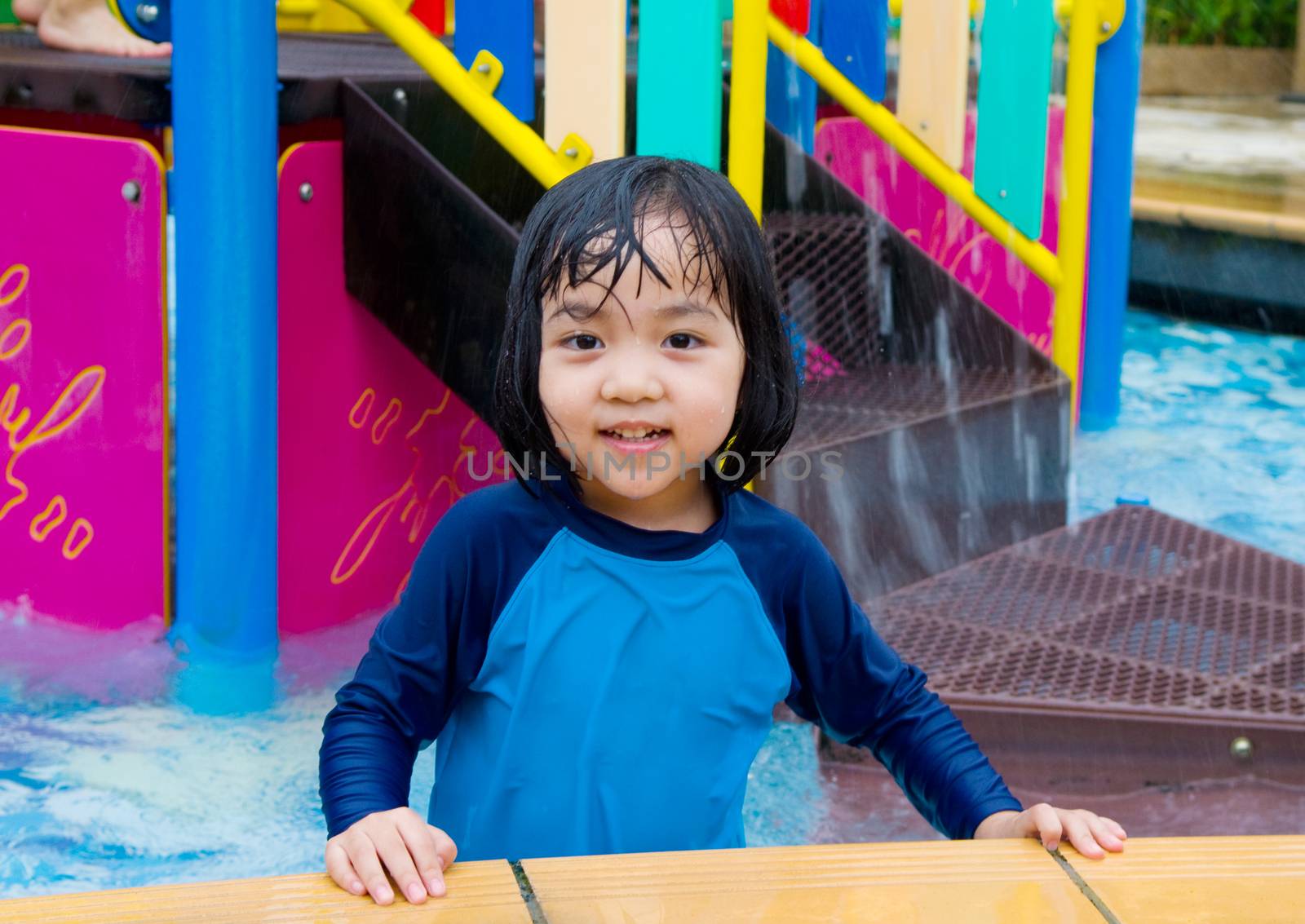 Happy asian girl has fun playing in water park