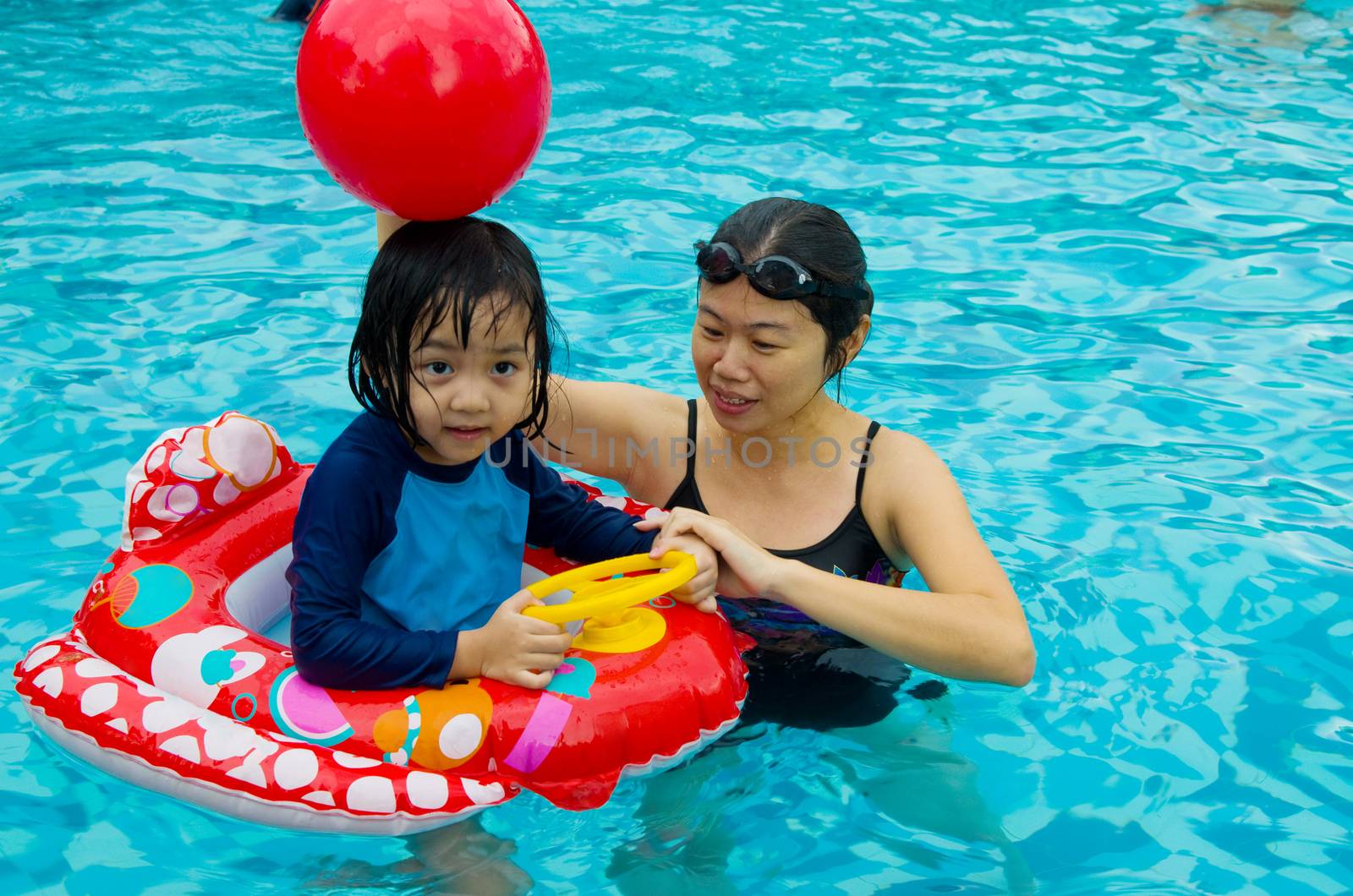 asian family in swim tube playing on swimming pool