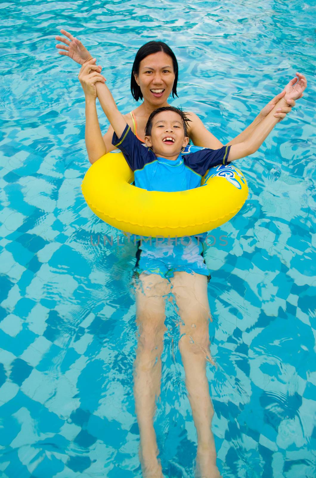 asian family in swim tube playing on swimming pool