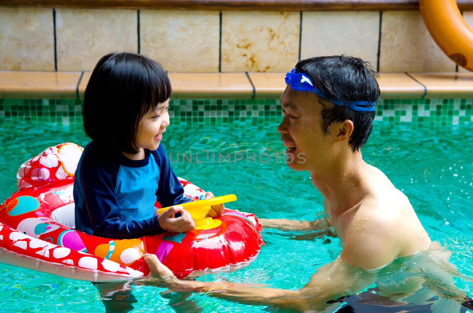 asian family in swim tube playing on swimming pool