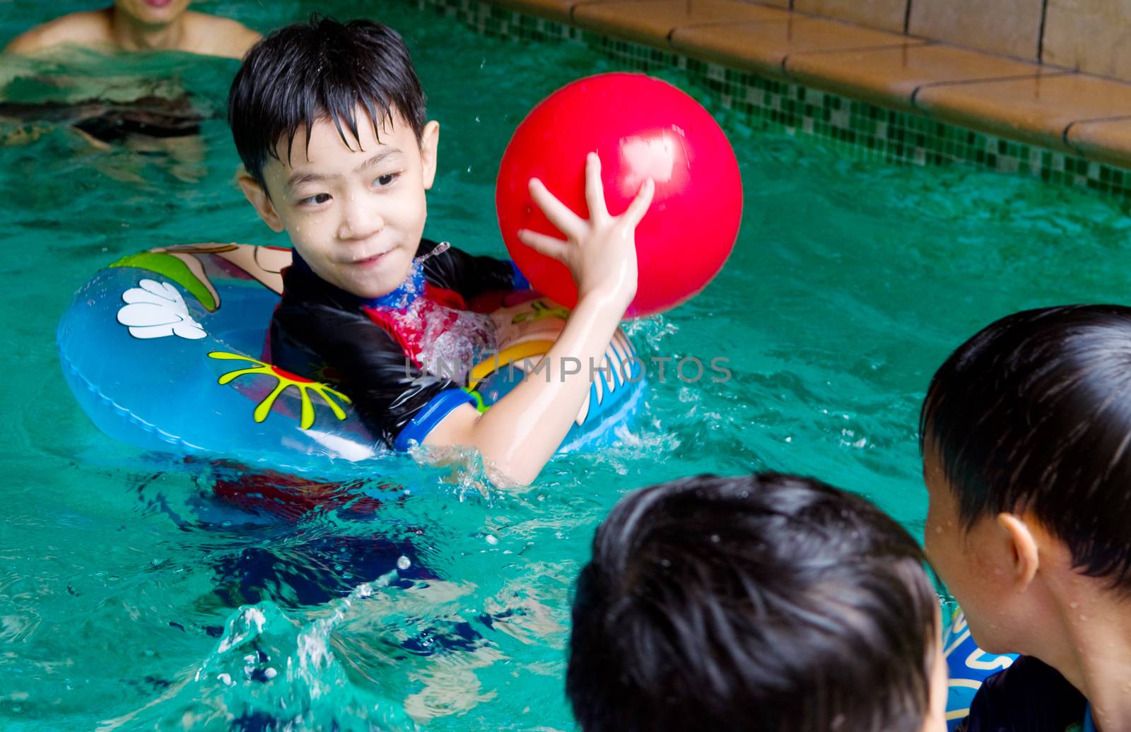 asian child in swim tube playing on swimming pool