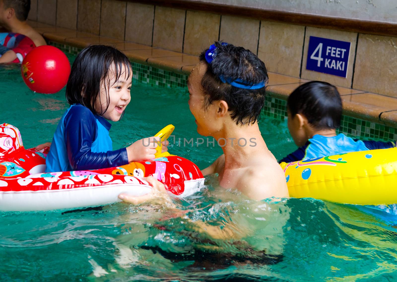 asian family in swim tube playing on swimming pool