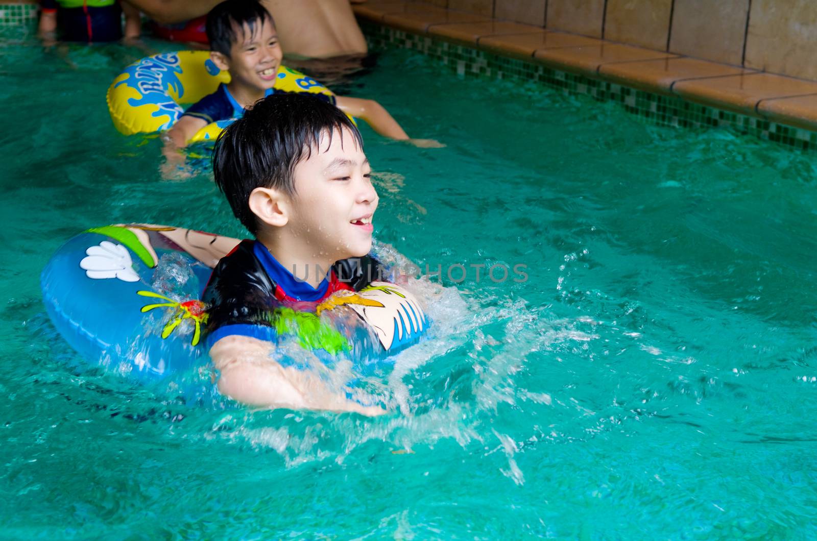 asian childs in swim tube playing on swimming pool