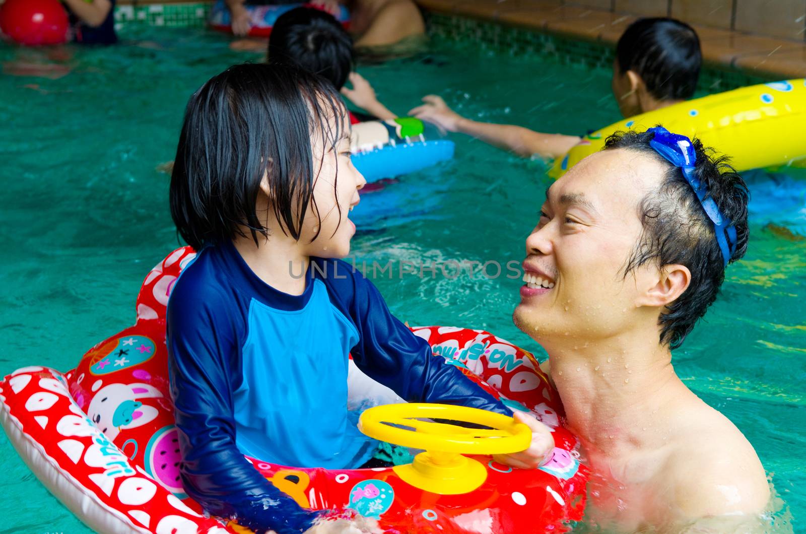 asian family in swim tube playing on swimming pool