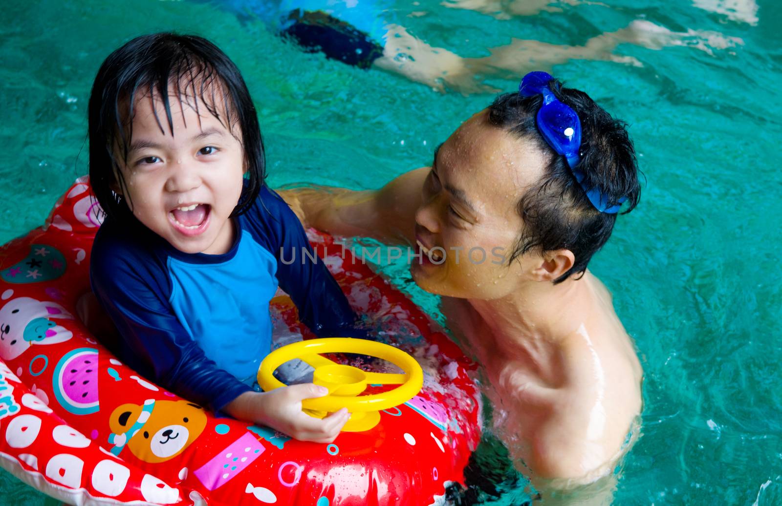 asian family in swim tube playing on swimming pool