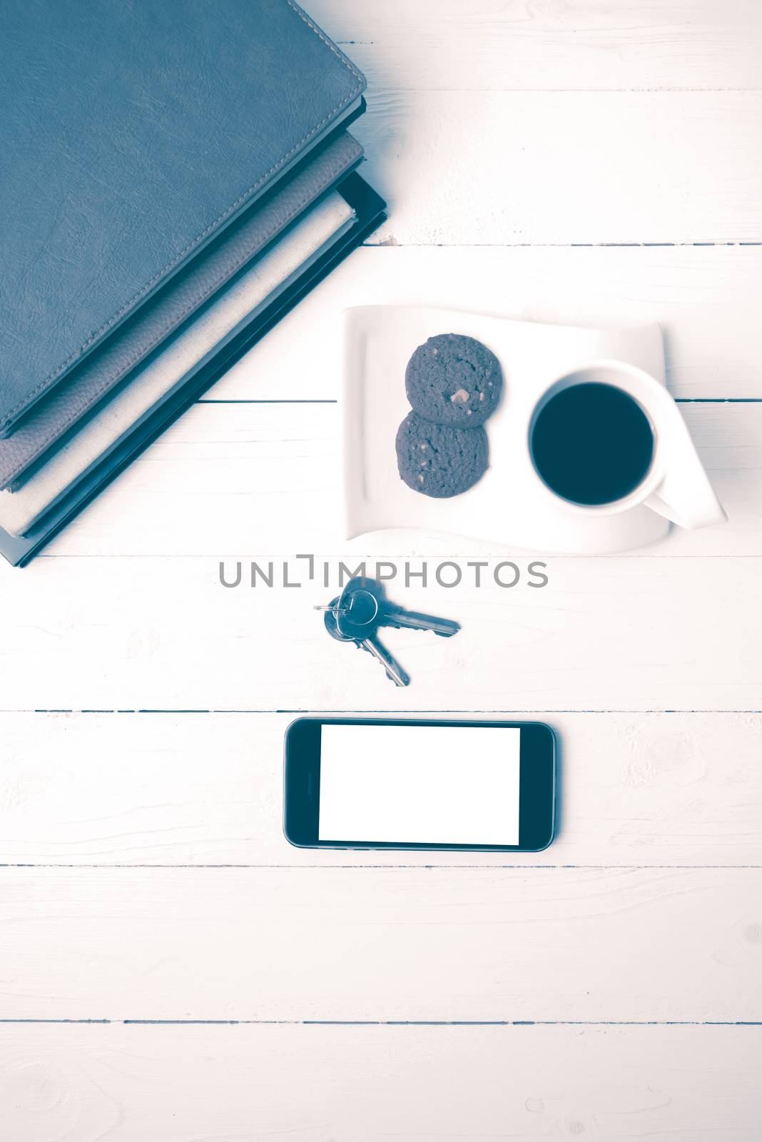 coffee cup with cookie,phone,stack of book and key on white wood table vintage style