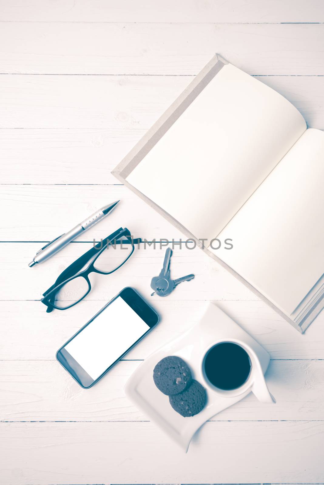 coffee cup with cookie,phone,open notebook and eyeglasses on white wood table vintage style