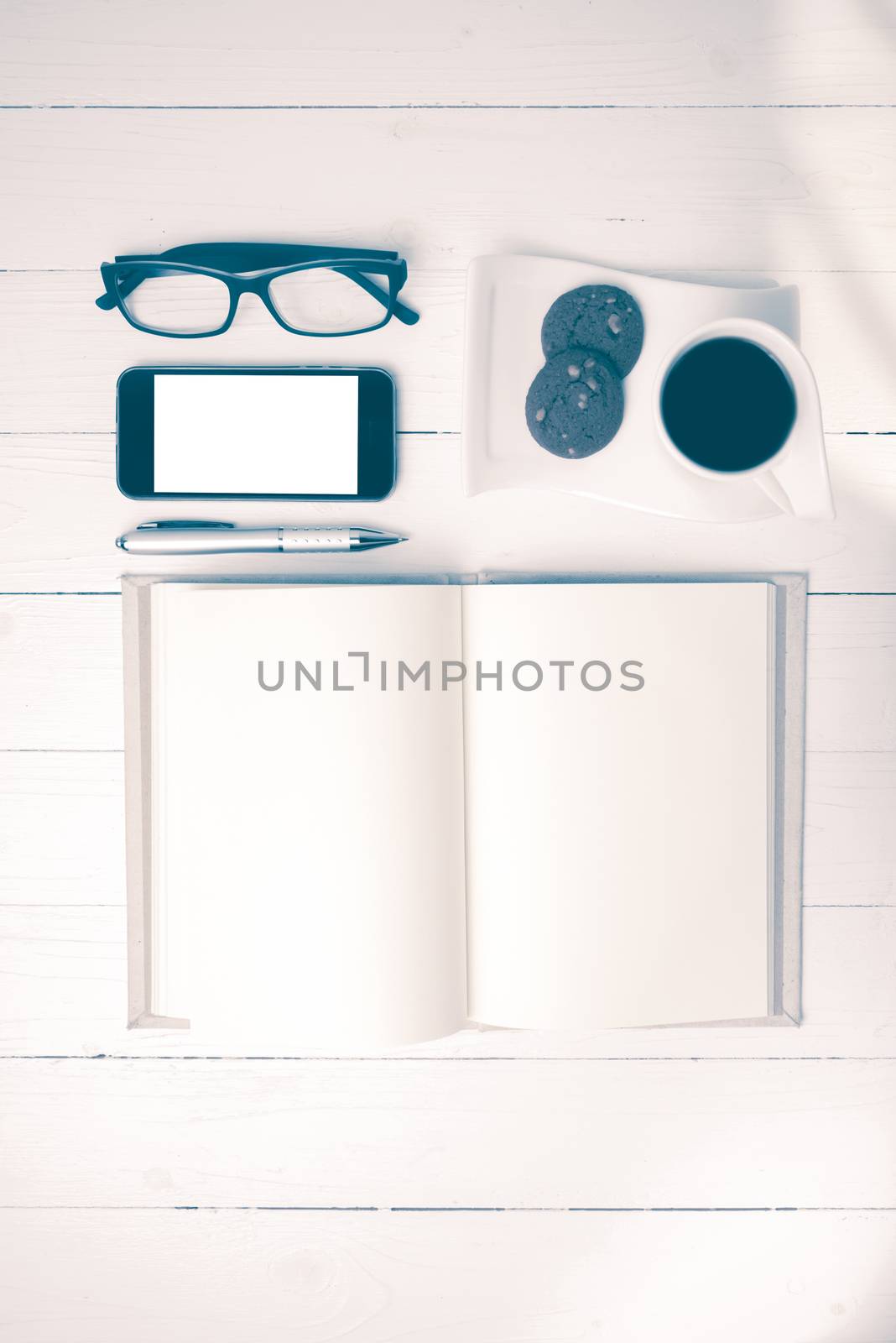 coffee cup with cookie,phone,notebook and eyeglasses on white wood table vintage style