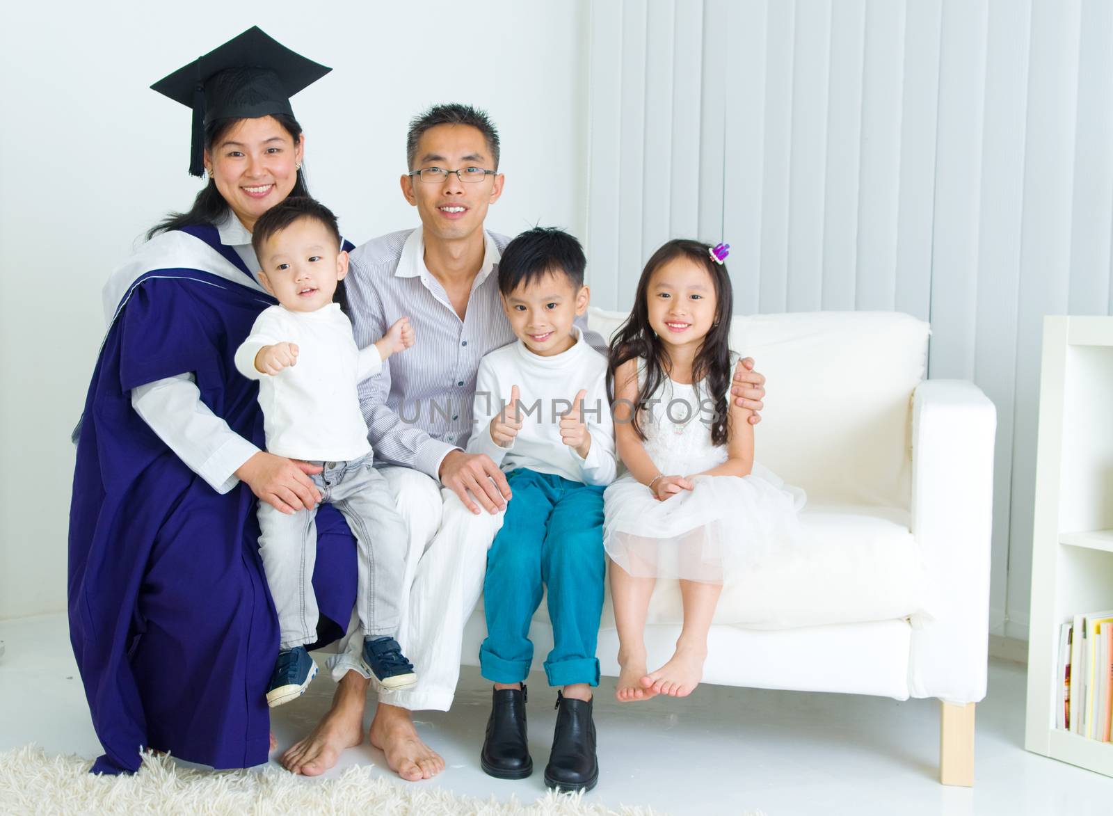 Asian mother in graduation gown.Taking photo with family.