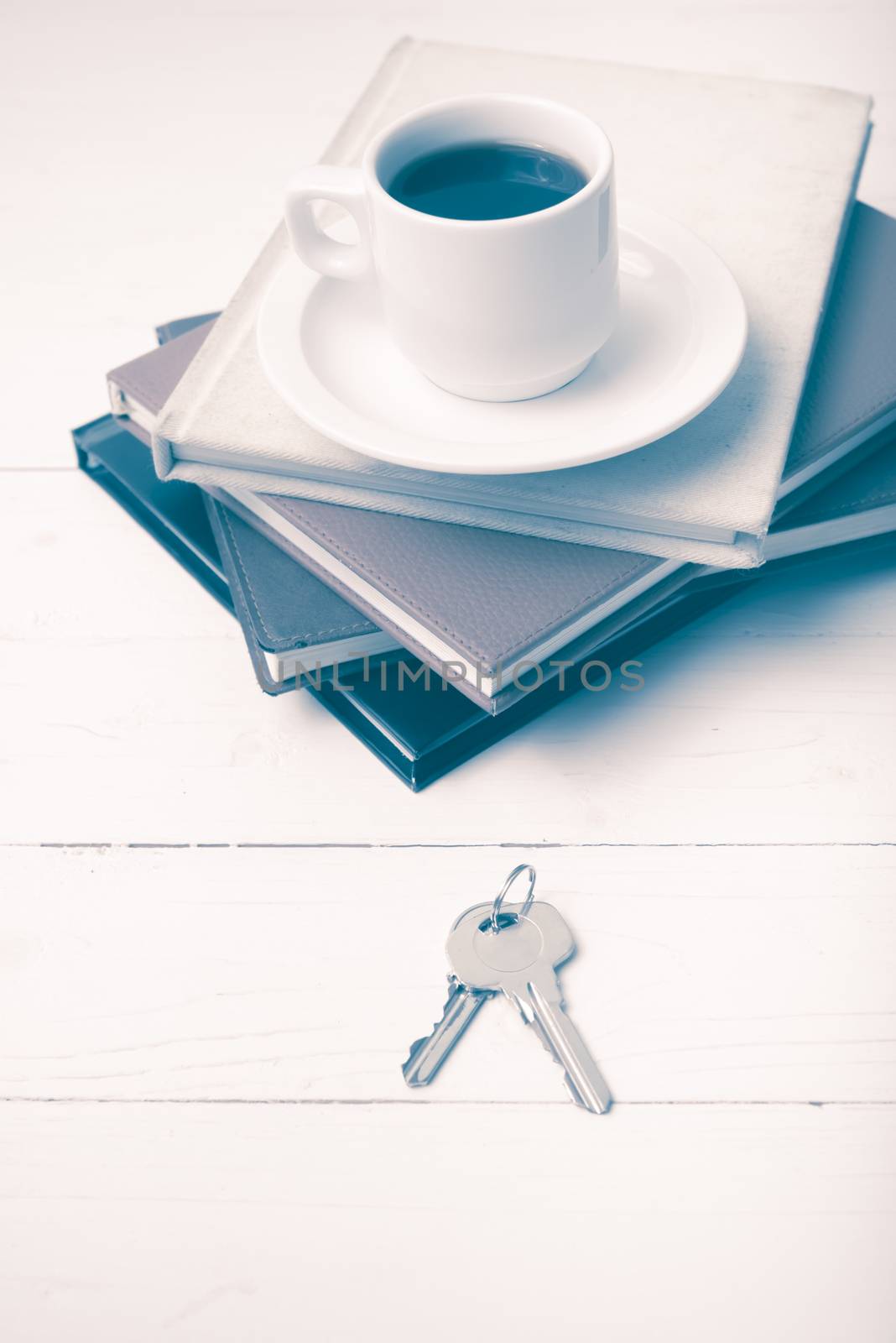 coffee cup,key and stack of book on white wood table vintage style