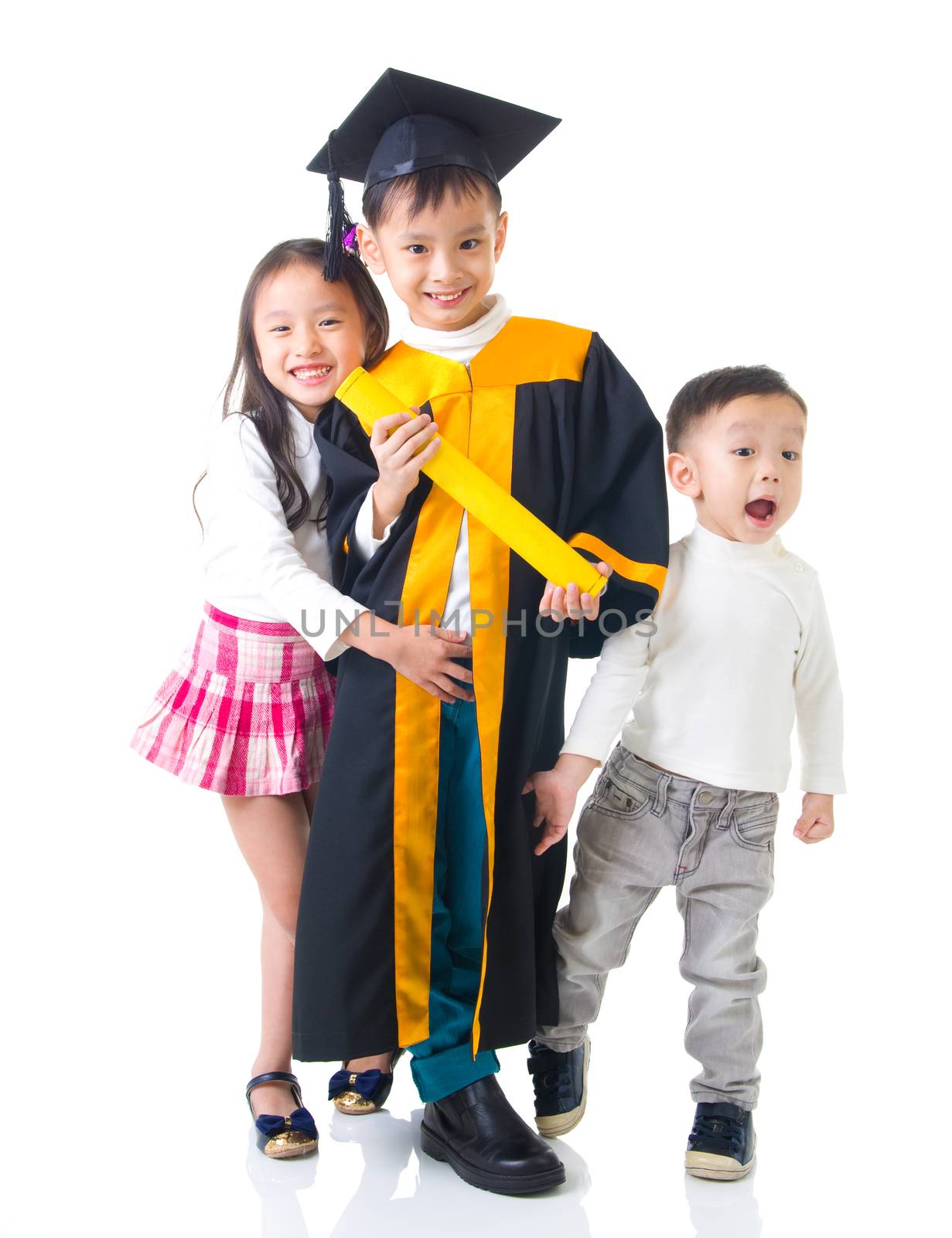 Asian school kid graduate in graduation gown and cap. Taking photo with sister and brother.