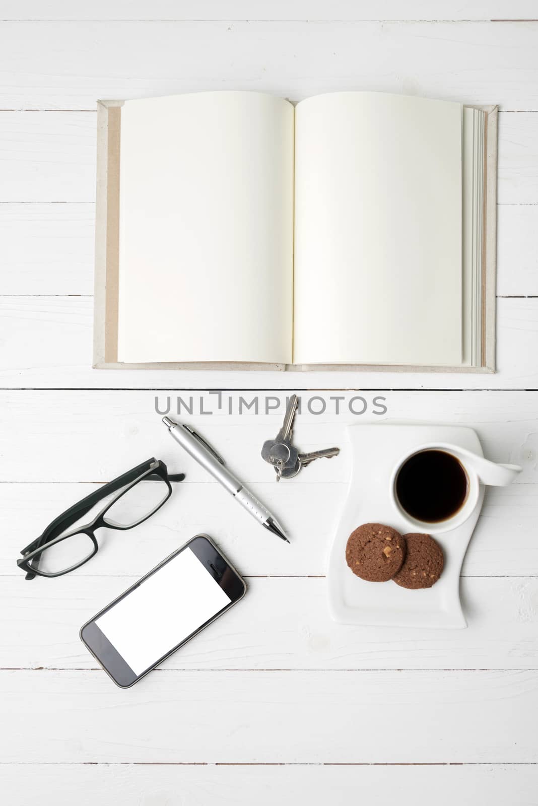 coffee cup with cookie,phone,open notebook and eyeglasses on white wood table