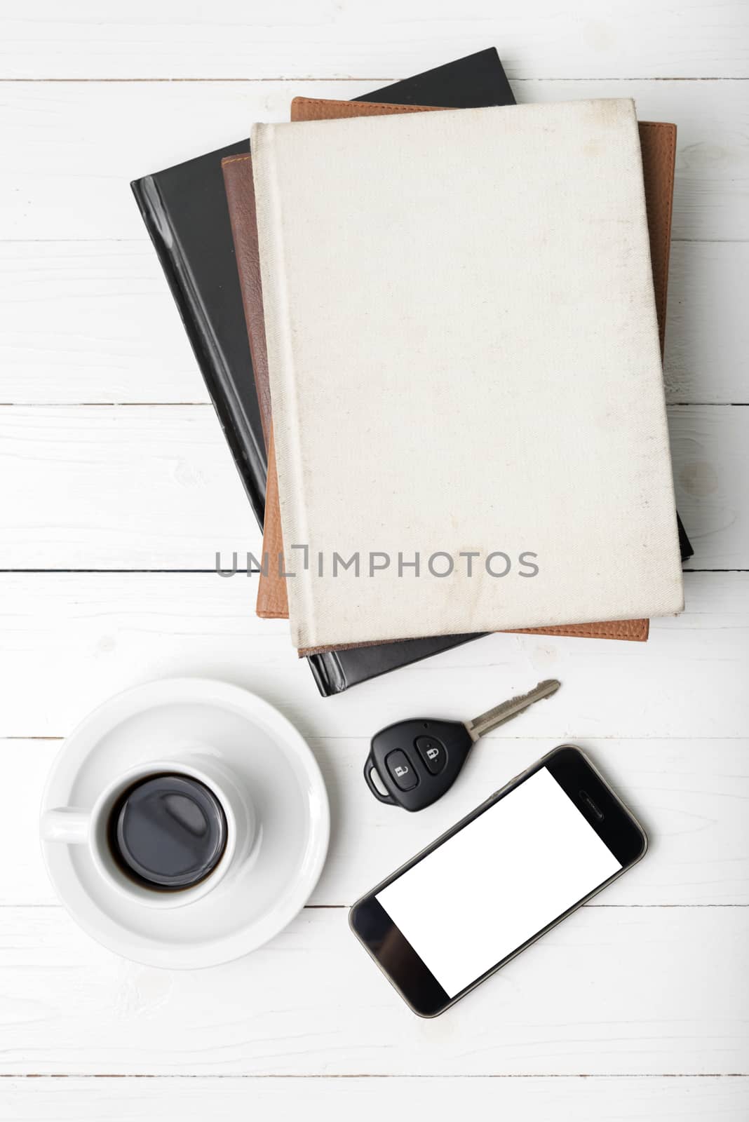 coffee cup with phone,car key and stack of book on white wood table