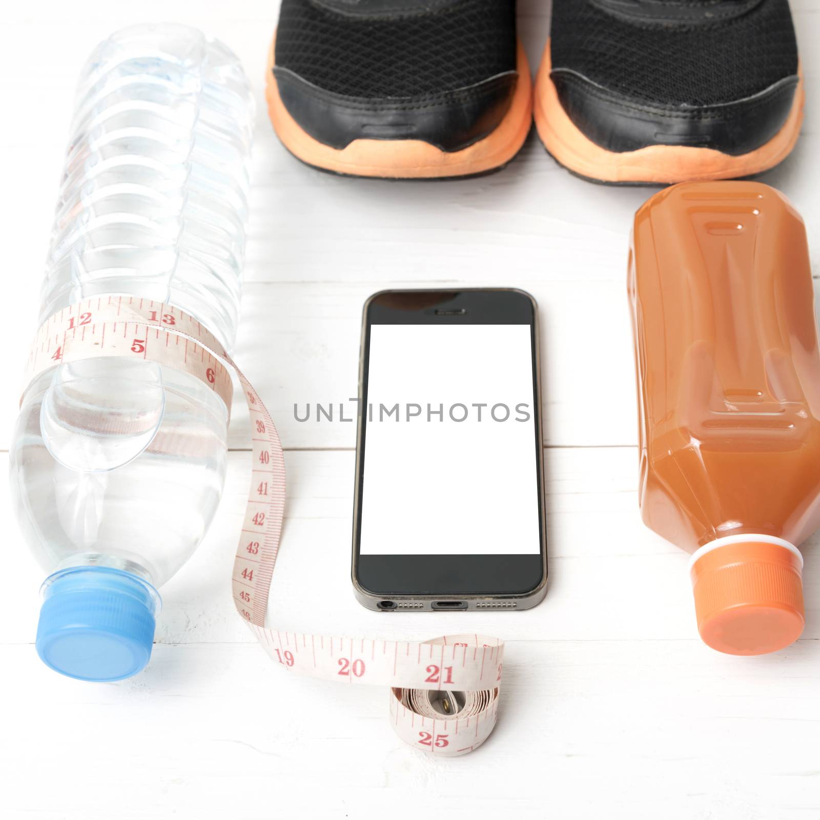 fitness equipment:running shoes,measuring tape,water,juice and phone on white wood background