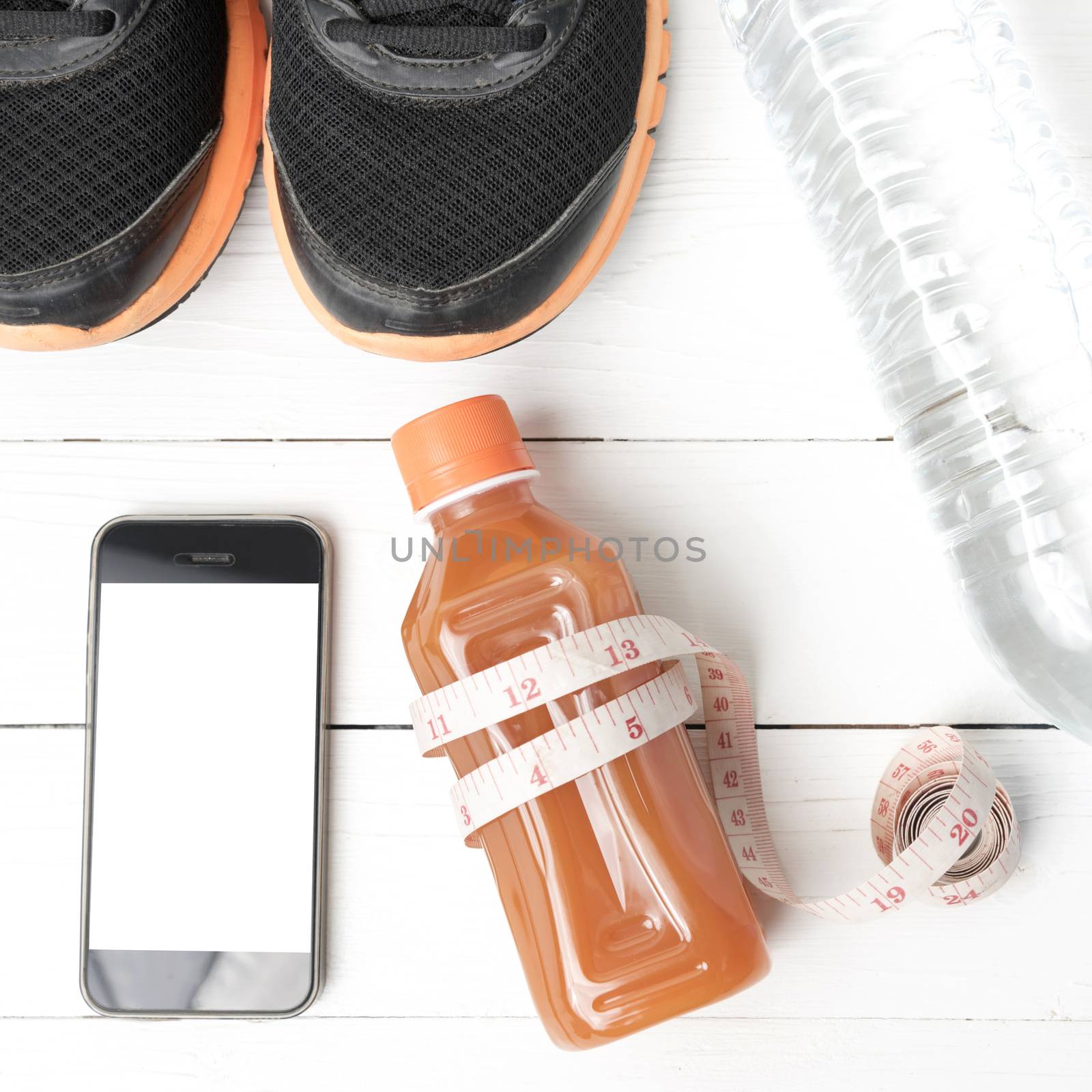 fitness equipment:running shoes,measuring tape,water,juice and phone on white wood background