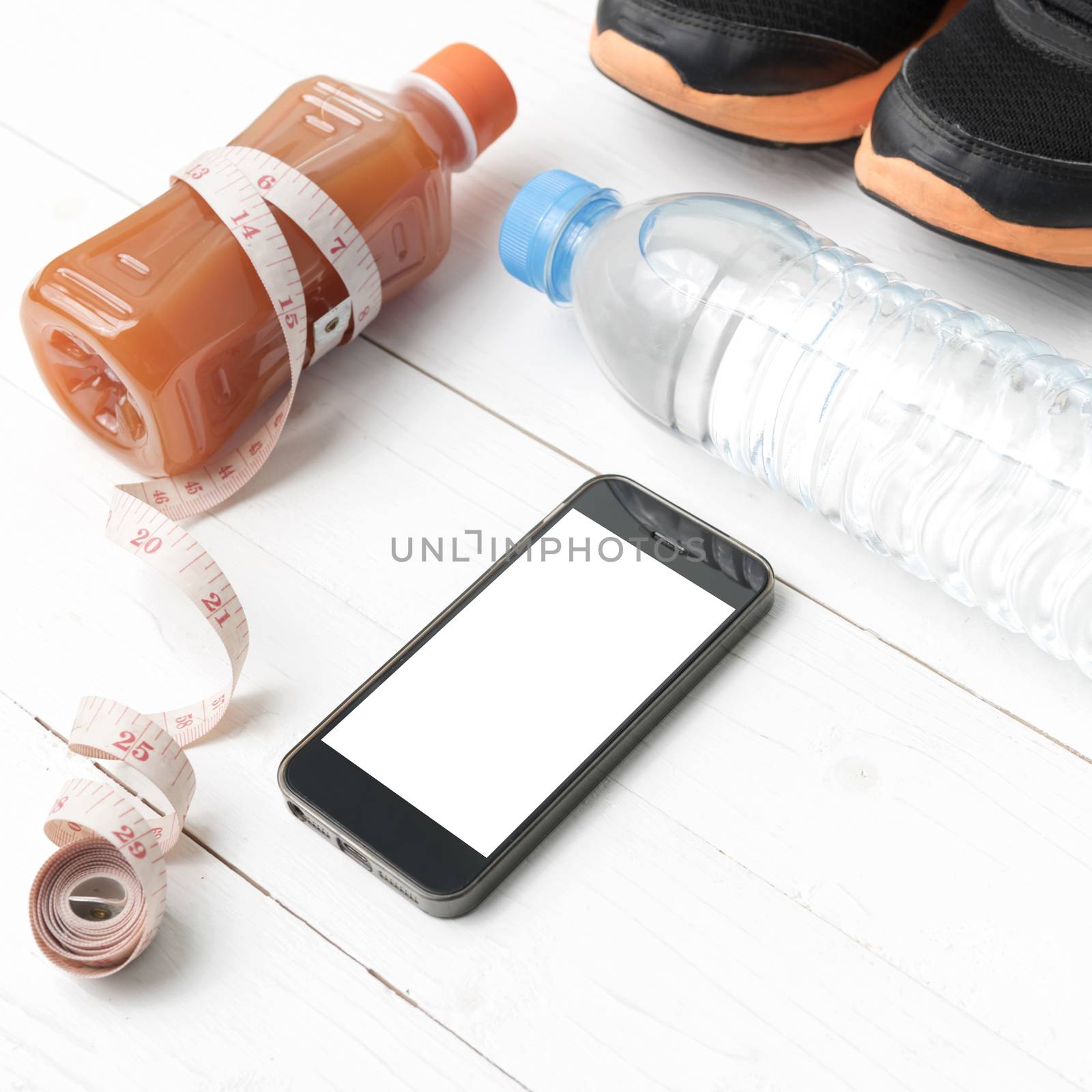 fitness equipment:running shoes,measuring tape,water,juice and phone on white wood background