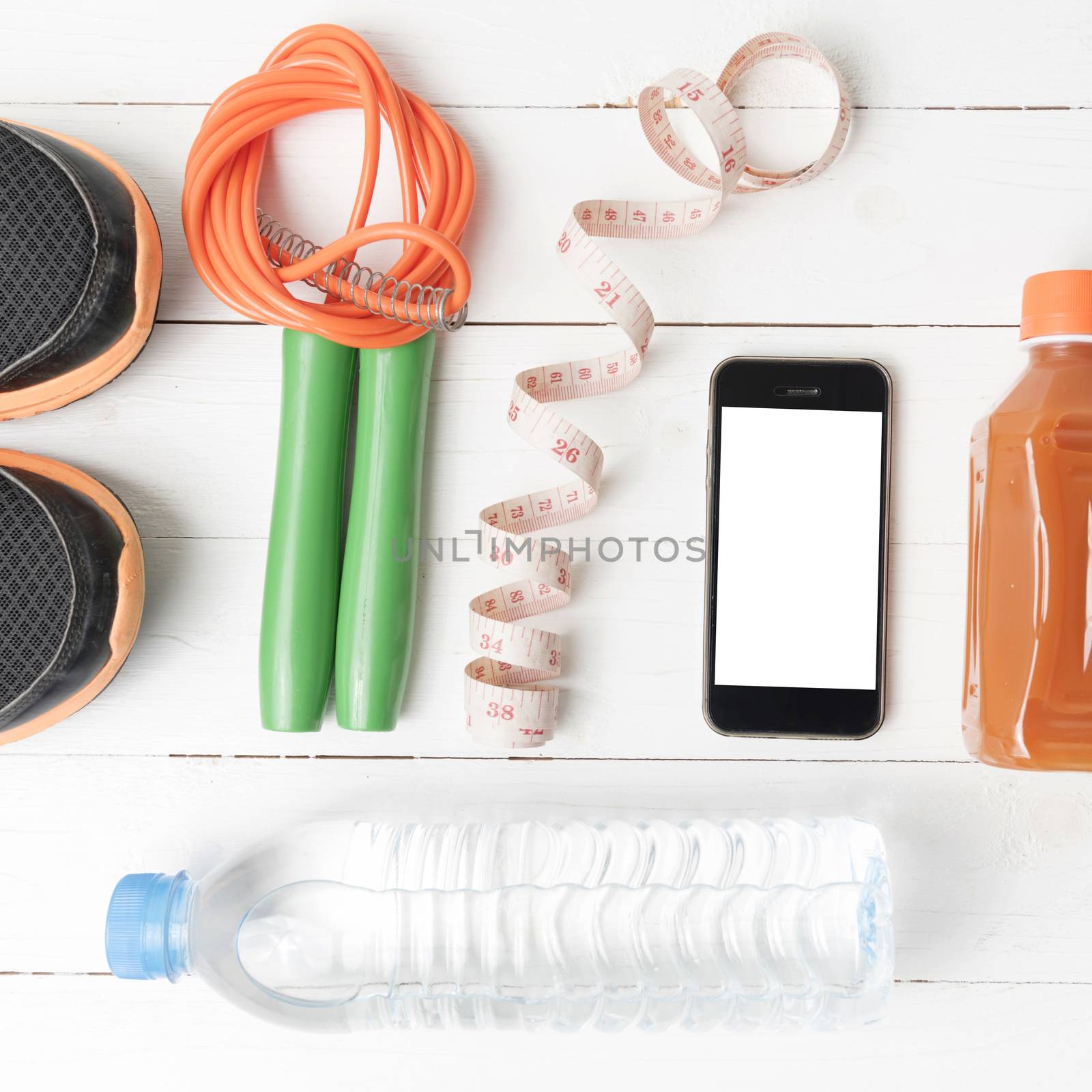 fitness equipment:running shoes,phone,measuring tape,water,juice and jumpong rope on white wood background