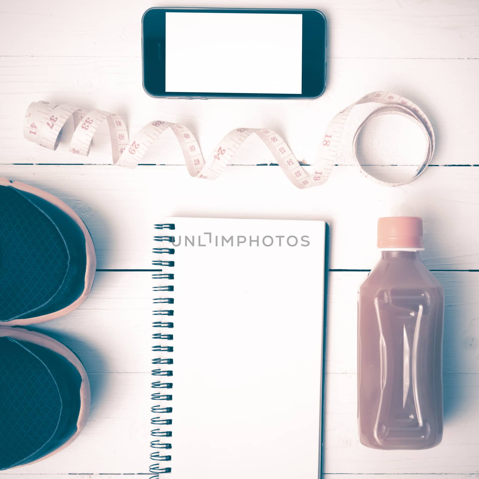 fitness equipment:running shoes,juice,measuring tape,notepad and phone on white wood background vintage style