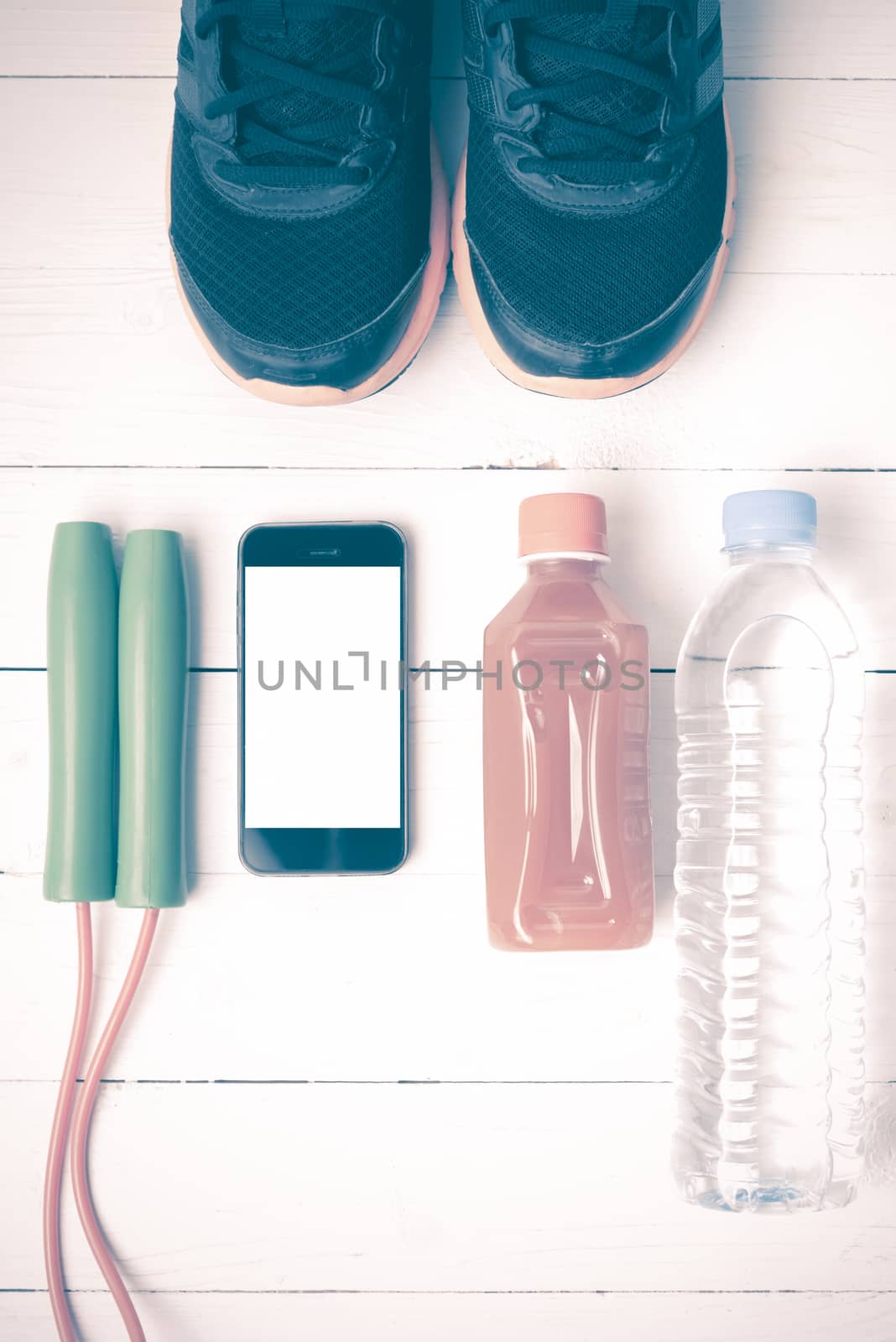 fitness equipment : running shoes,jumping rope,water,juice and phone on white wood background vintage style