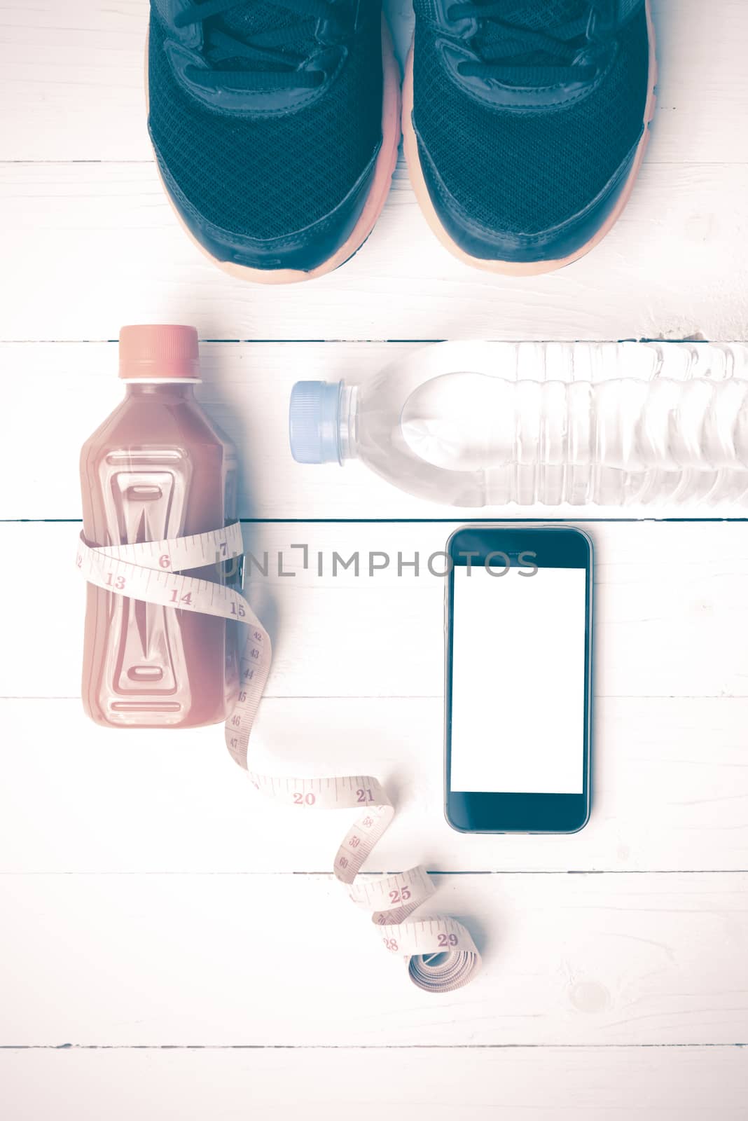 fitness equipment:running shoes,measuring tape,water,juice and phone on white wood background vintage style