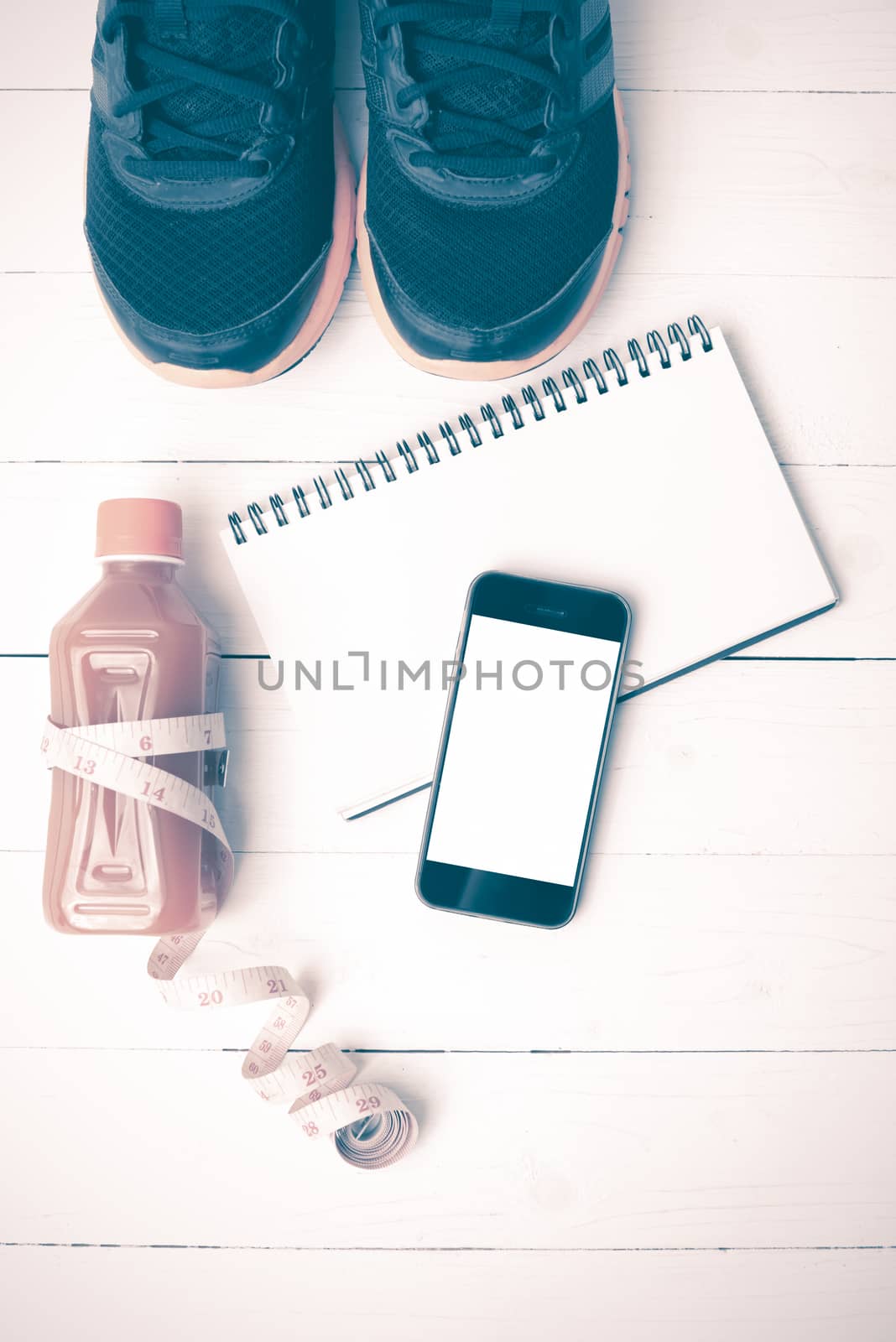 fitness equipment:running shoes,juice,measuring tape,notepad and phone on white wood background vintage style