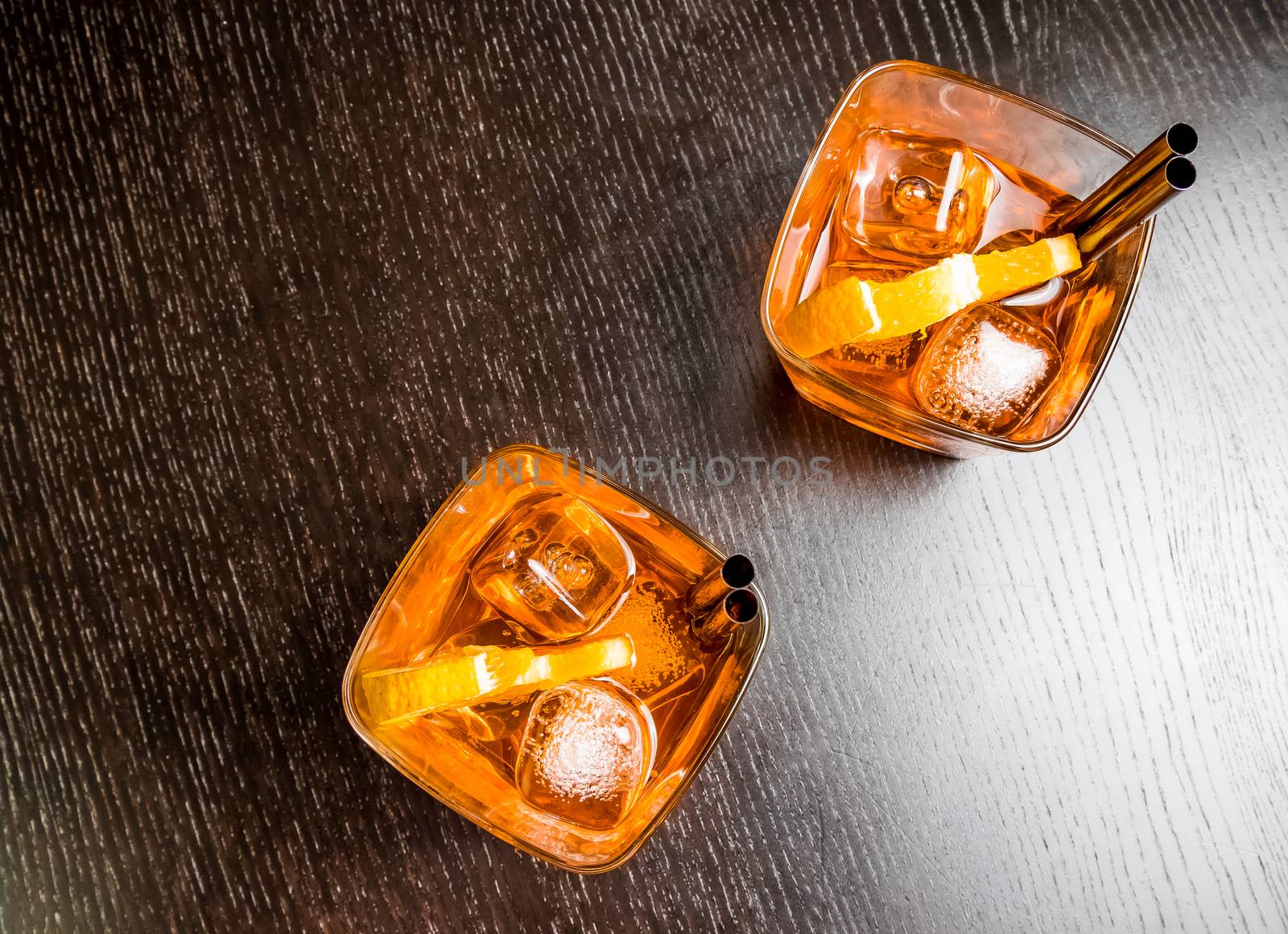top of view of two glasses of spritz aperitif aperol cocktail with orange slices and ice cubes on wood table
