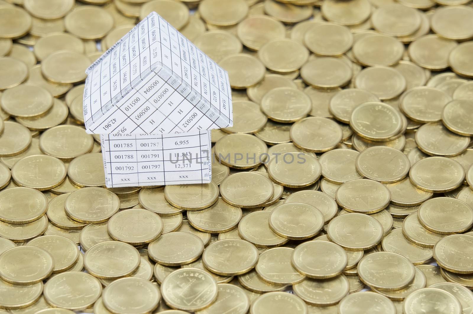 Paperwork as house on stack of gold coins as gold background. 