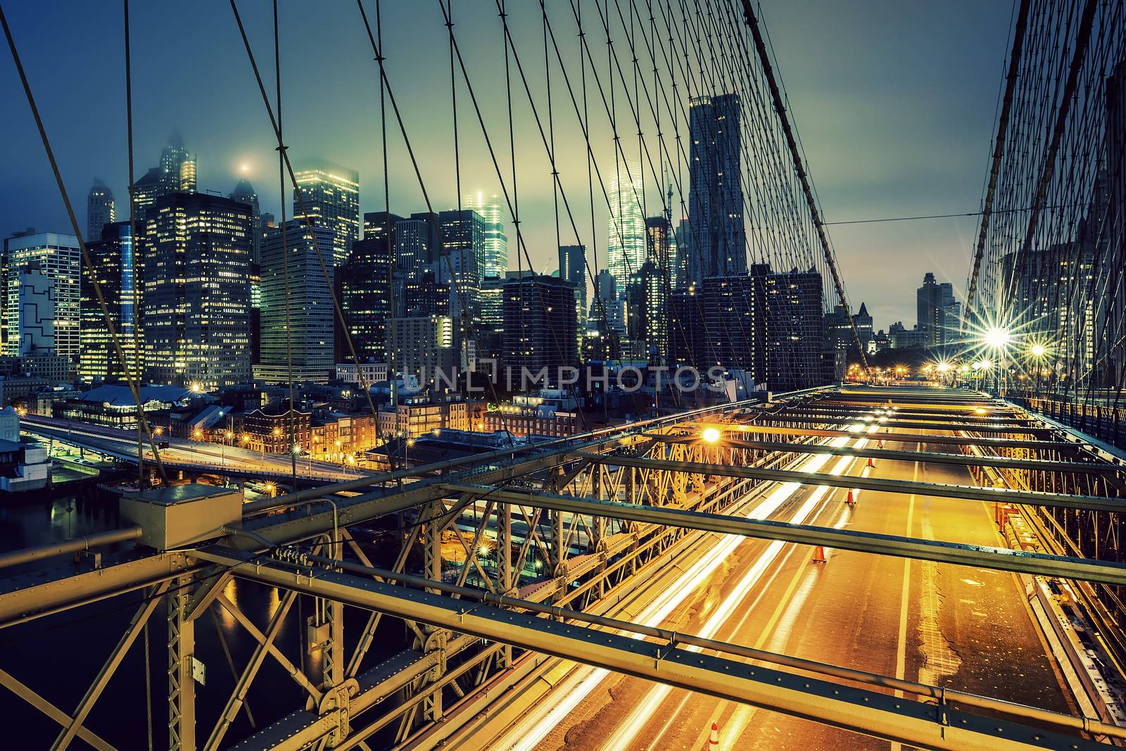 On Brooklyn Bridge at night with car traffic, NY.