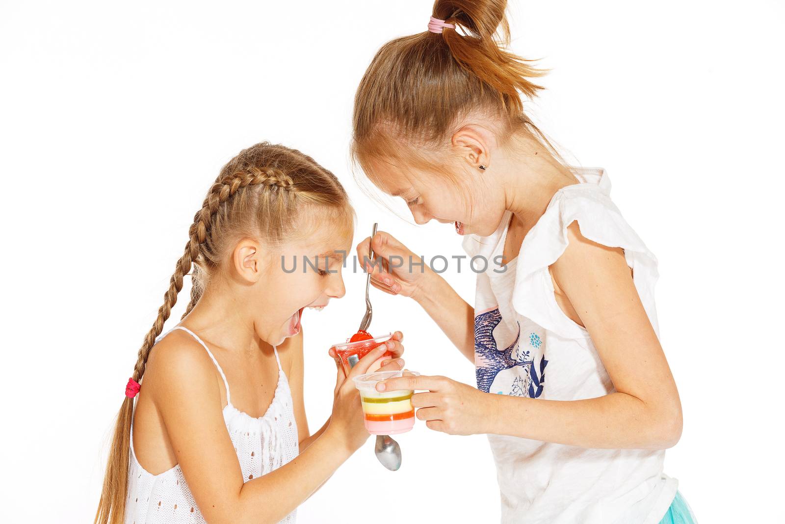 Beautiful little girls in white dress eating jelly
