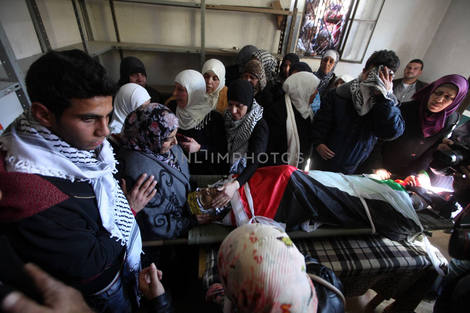 WEST BANK, Bethlehem: The mother of a Palestinian man identified as Srur Ahmad Abu Srur and who was shot and killed during clashes with Israeli security forces, looks down at his son's corpse during the funeral ceremony at Aida refugee camp in Bethlehem, West Bank on January 13, 2016.The corpse was buried at Aida refugee camp a day after the Palestinian man was allegedly shot in the chest by Israeli forces in Beit Jala, a Palestinian health ministry statement said. 