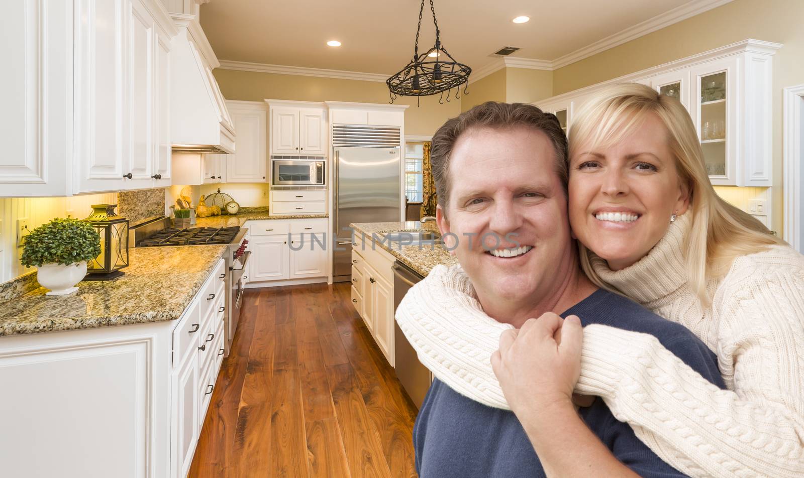 Happy Couple Hugging Inside Beautiful Custom Kitchen.