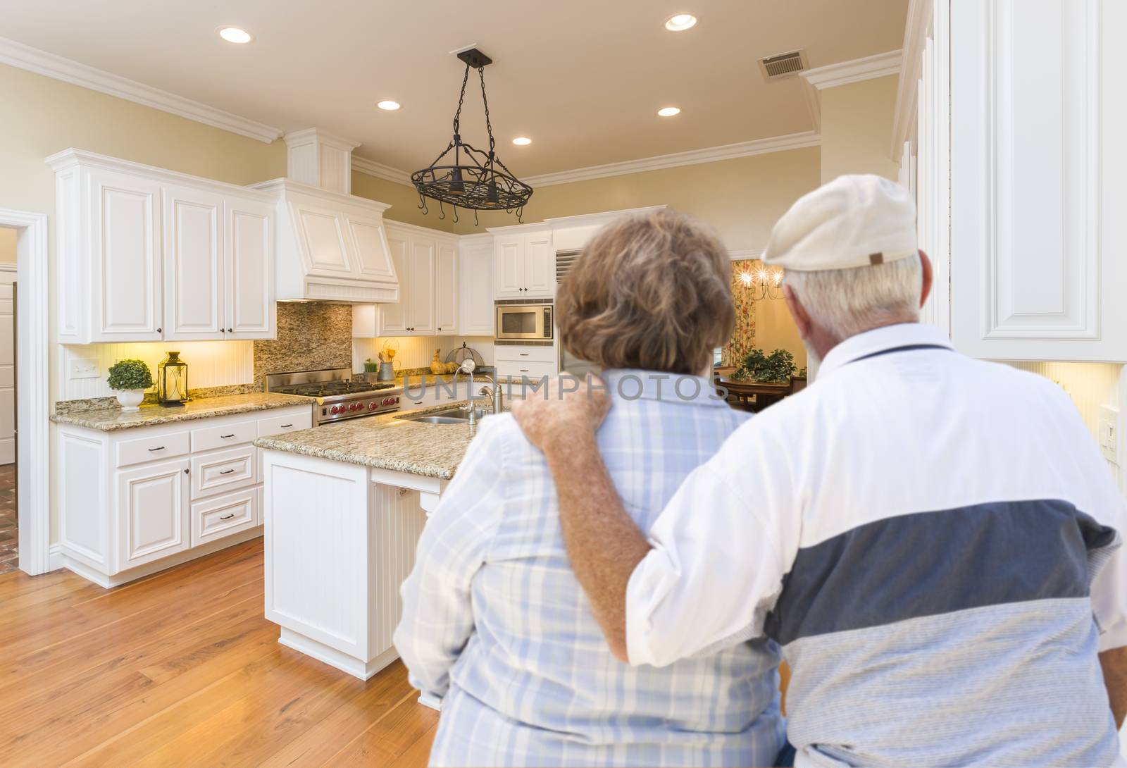 Happy Senior Couple Looking Over Beautiful Custom Kitchen Design.