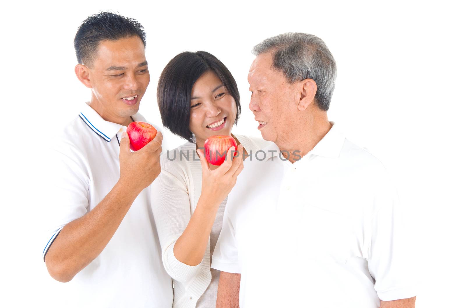 Happy Asian family sharing apple. Senior father with adult daughter and son eating red apple together.