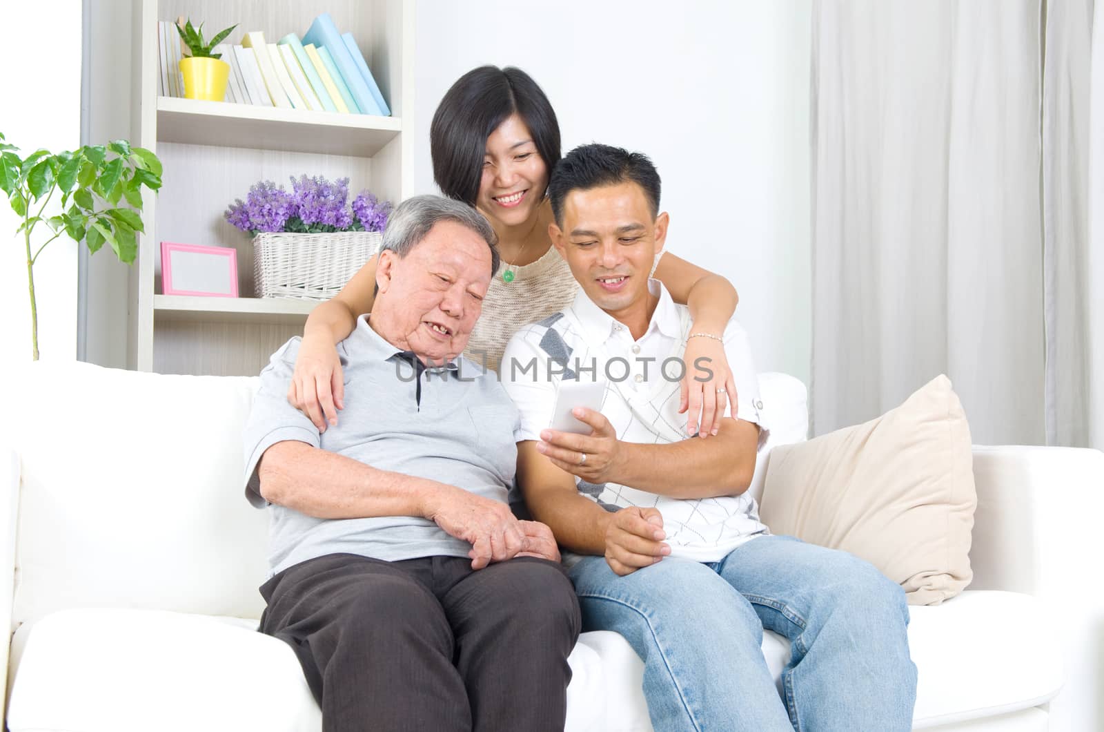 Modern technology, age and people concept. Asian senior man with his daughter and son taking selfie, using smartphone, self photographing.