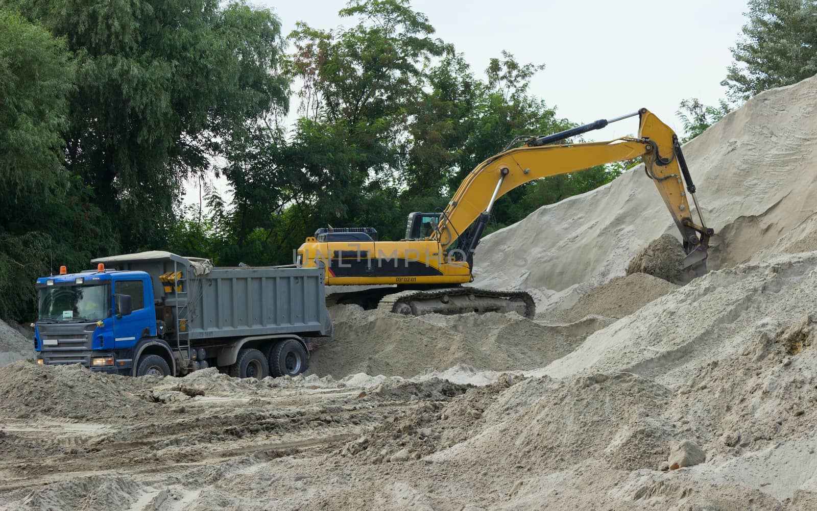 Excavator loads sand into the truck