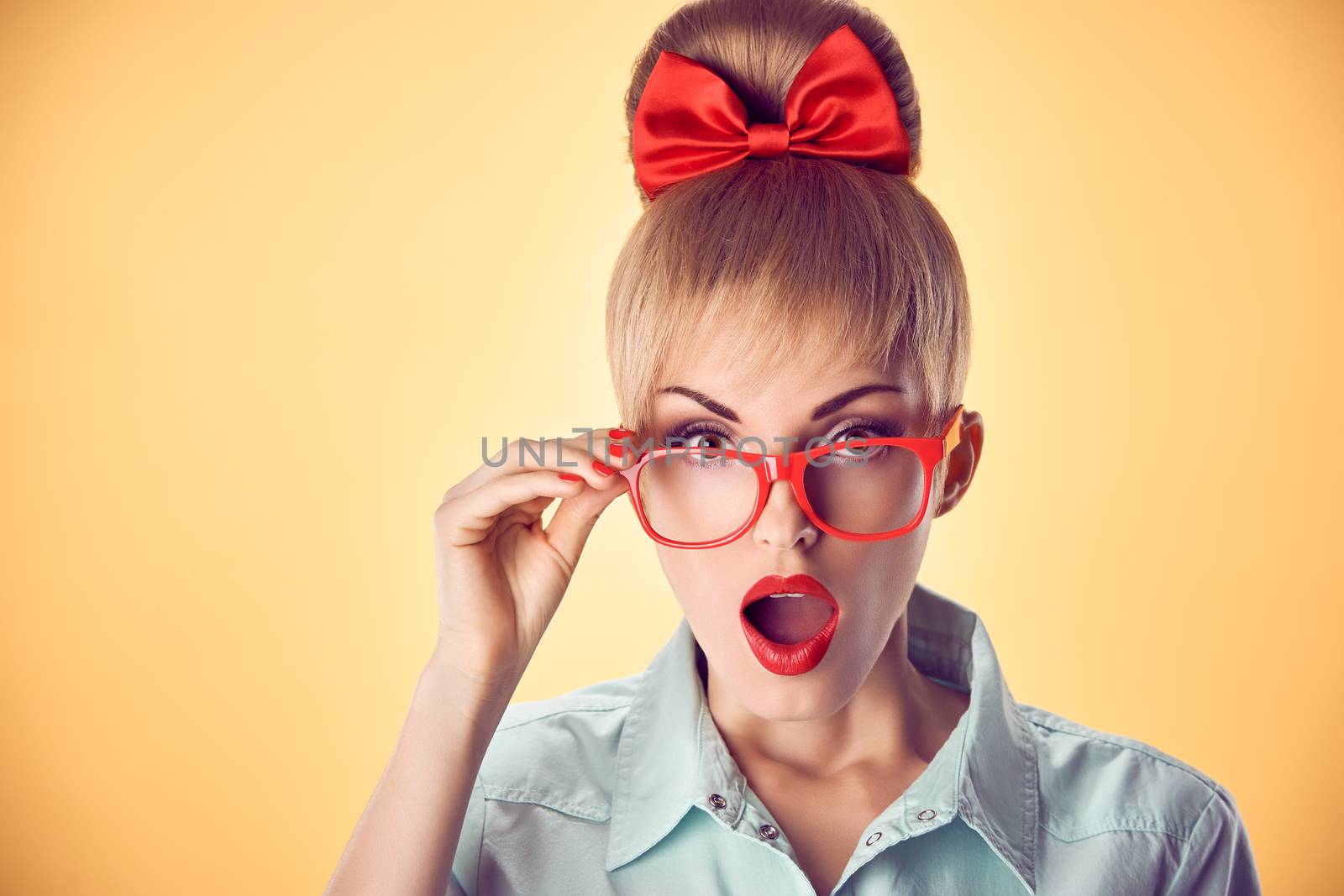 Beauty fashion portrait business woman, stylish red glasses surprised, open mouth, shocked. Attractive blonde girl,  confidence, Pinup hairstyle bow makeup.Unusual playful, emotions.Vintage, on yellow