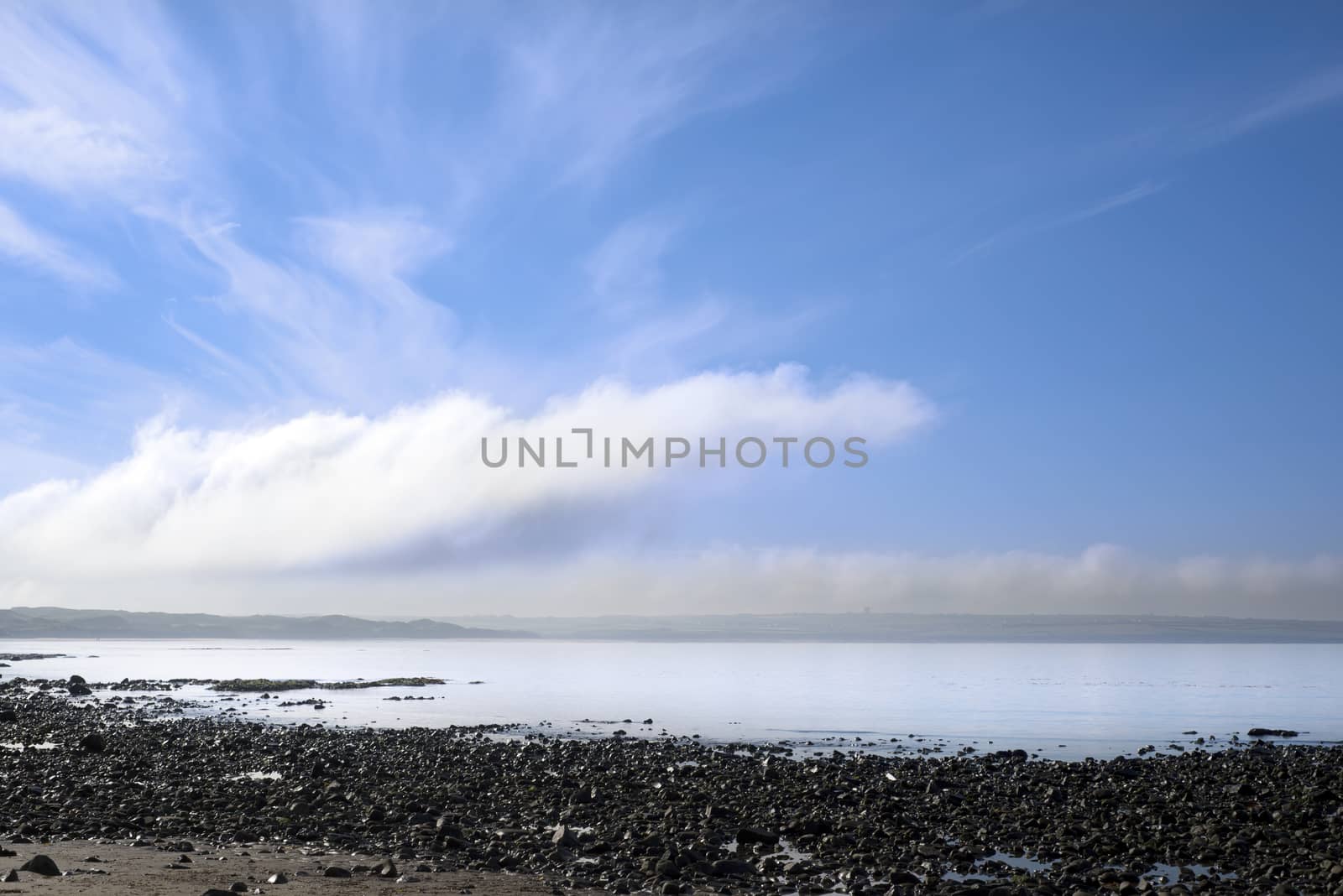 calm sky over the black rocks by morrbyte