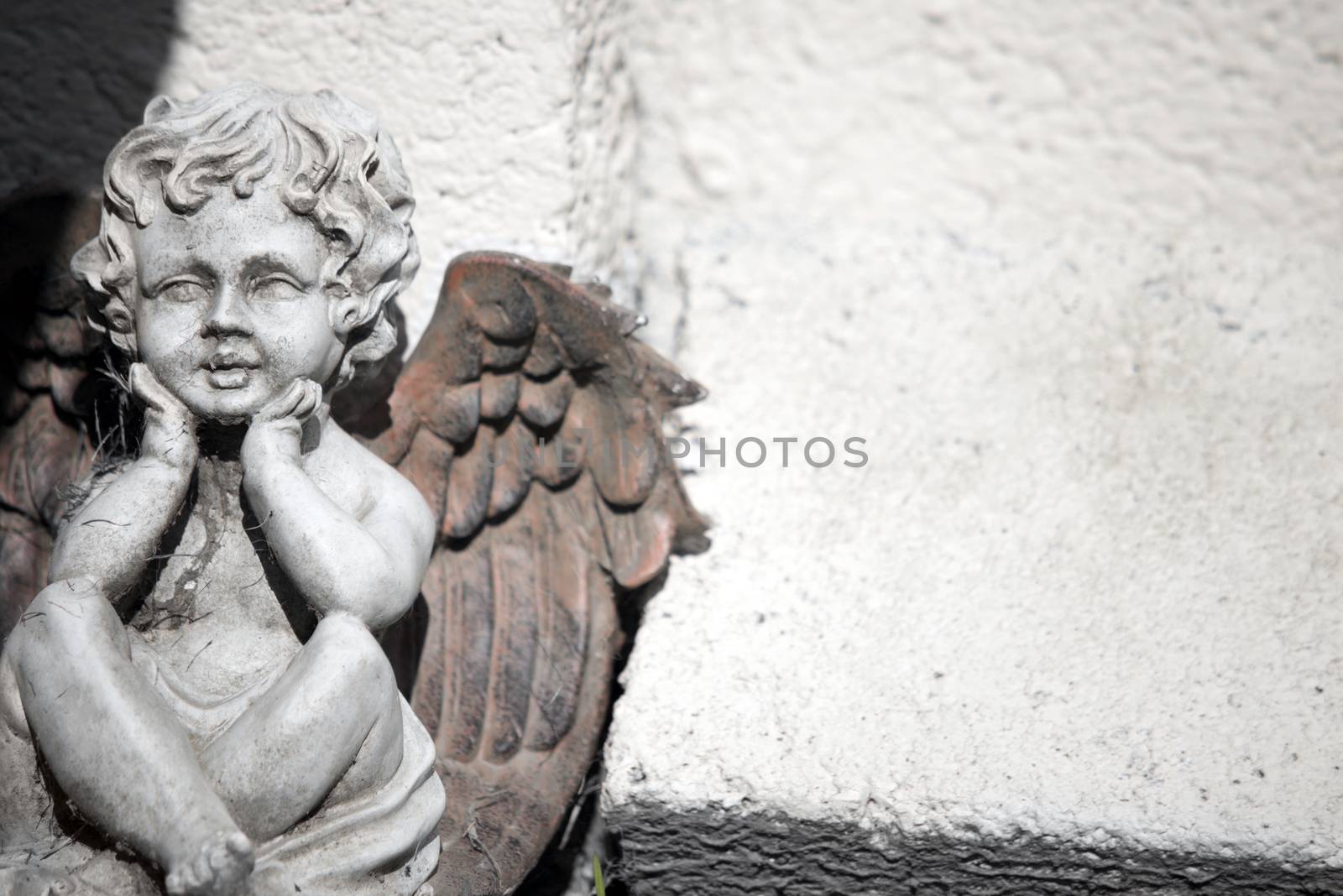 cherub statue against a wall by morrbyte