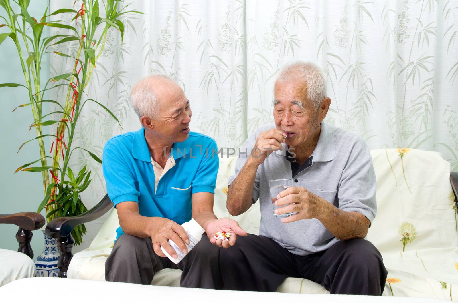 Asian senior man having medicine at home. Adult son caring for a senior man.
