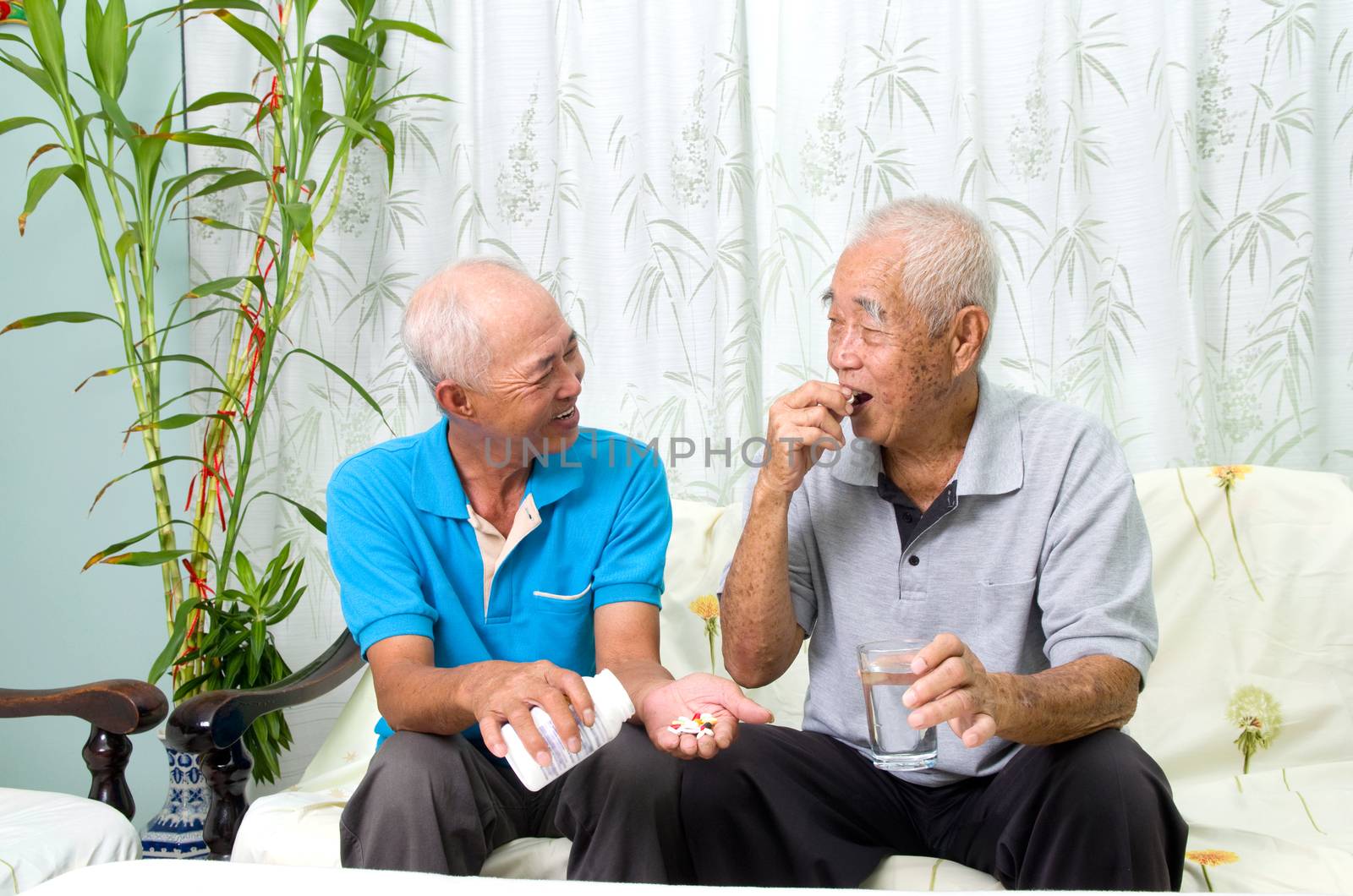 Asian senior man having medicine at home. Adult son caring for a senior man.