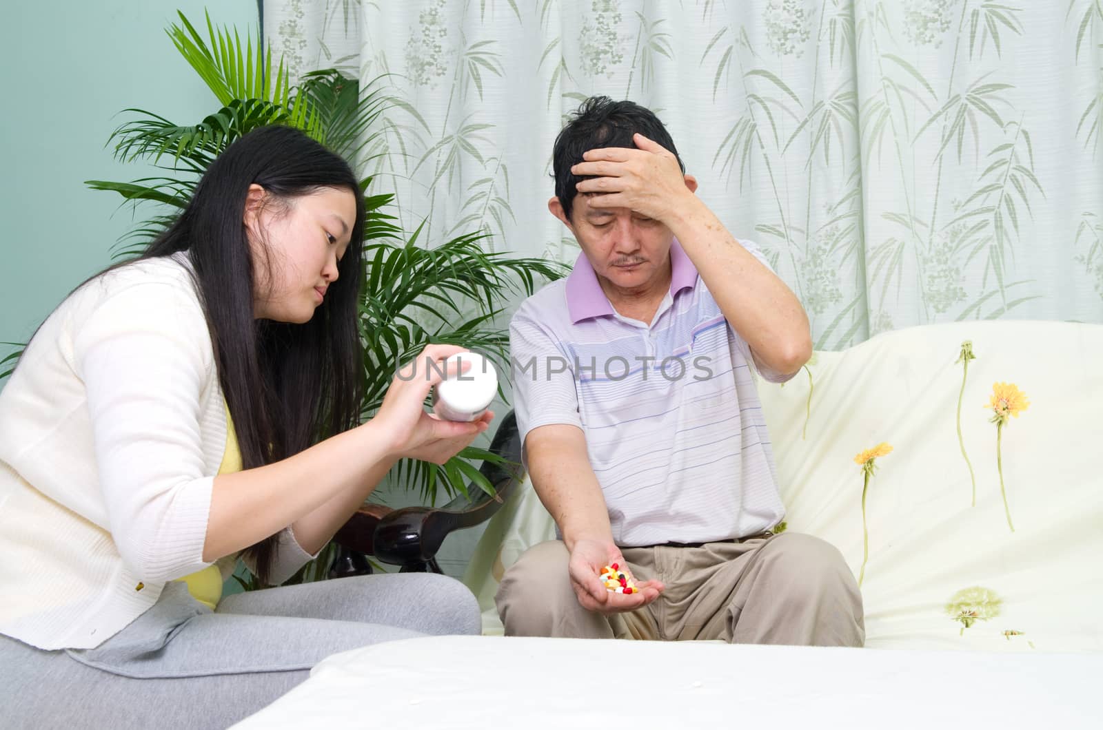 Asian man having medicine at home. Daughter take care of her father. 