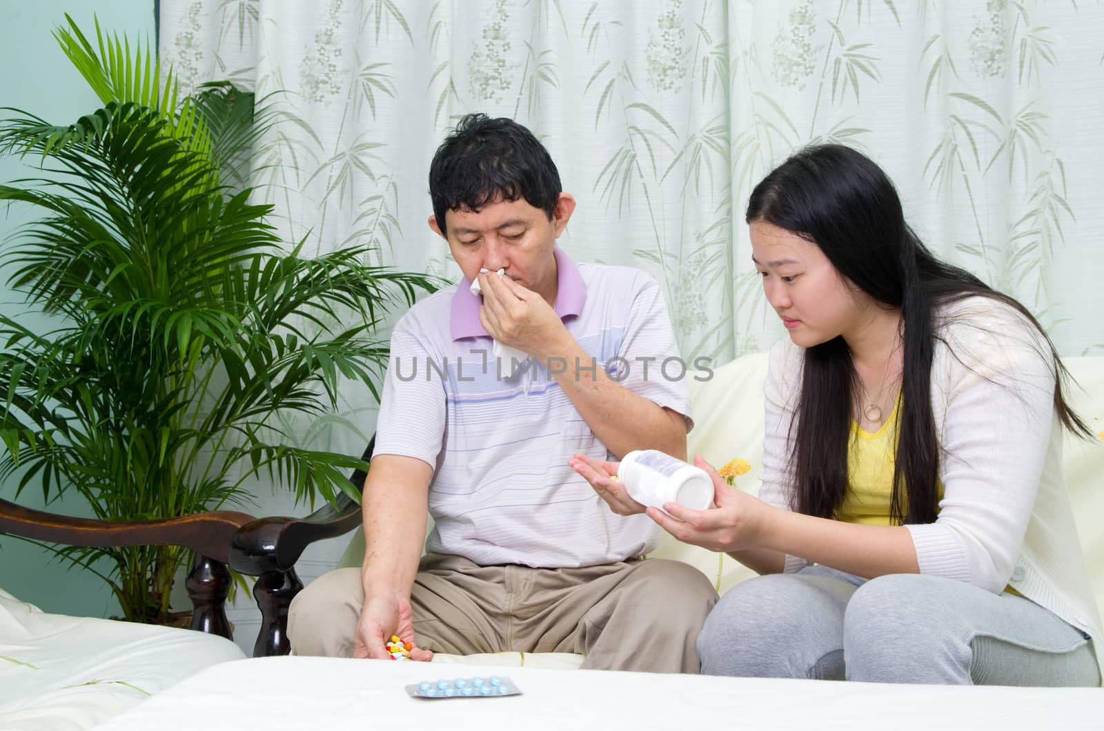 Asian man having medicine at home. Daughter take care of her father. 