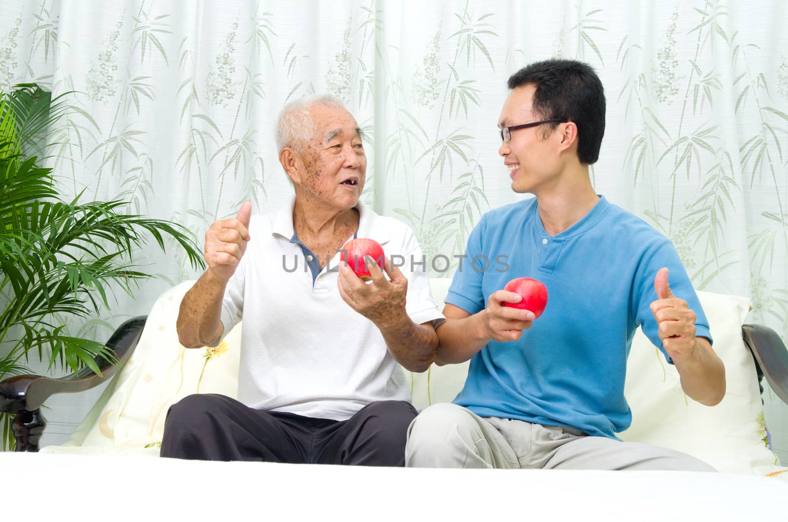 Asian senior man and son making okay sign while holding an apple