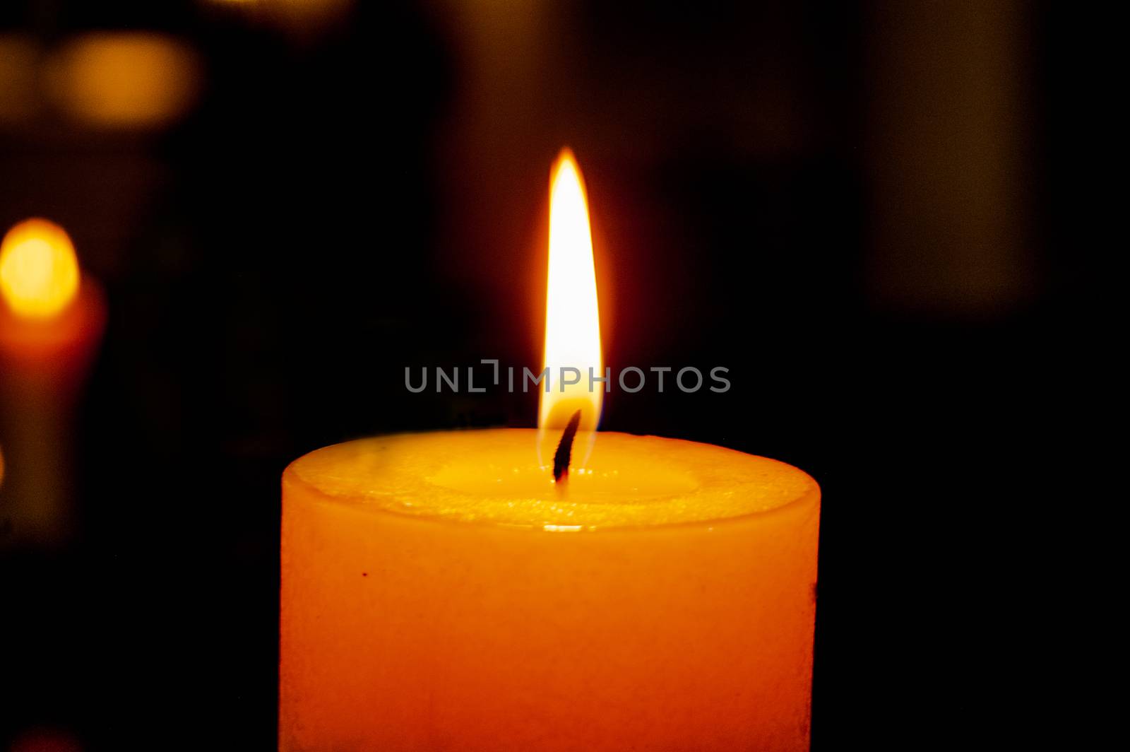 single burning candle on a dark background with reflection 
