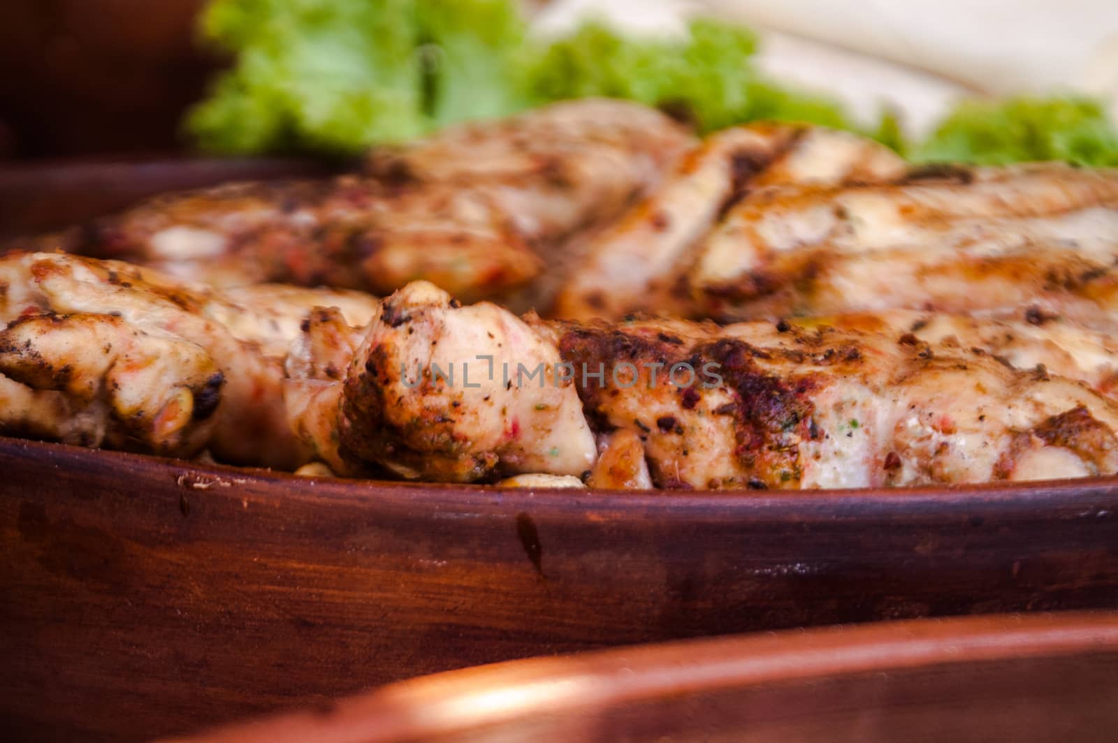 the tasty and juicy pieces of fried meat lying in a clay plate brown color