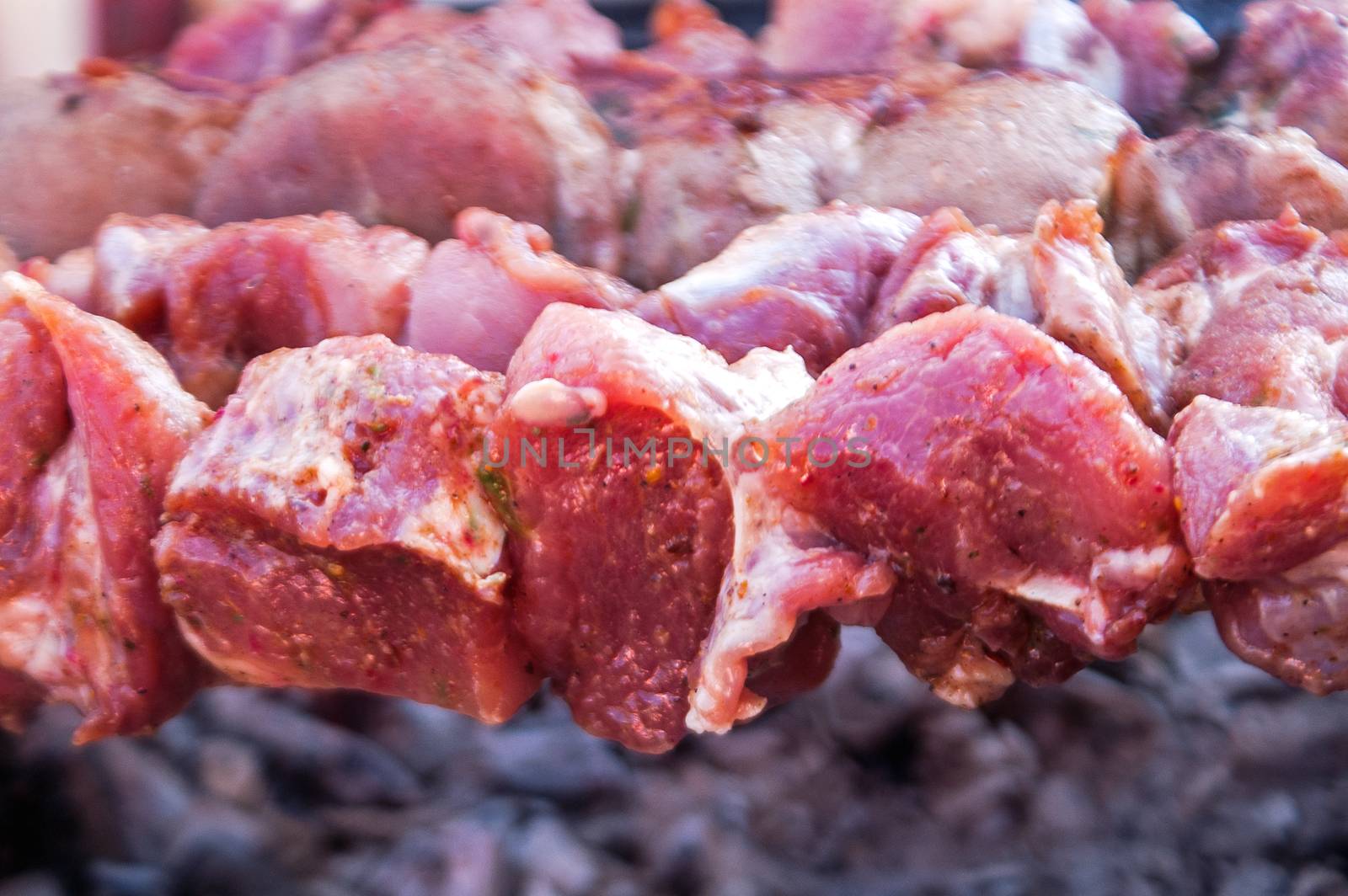 preparation of pieces of crude, marinated meat on a grill 