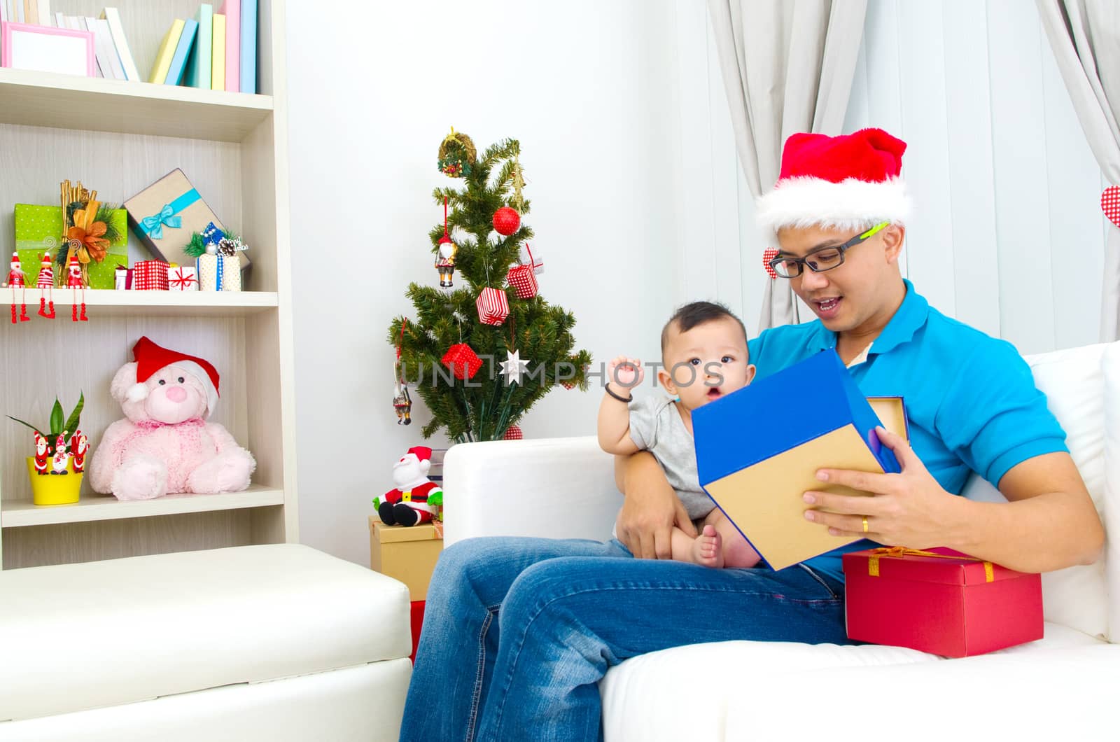 Portrait of happy father and his son in Santa caps on Christmas eve