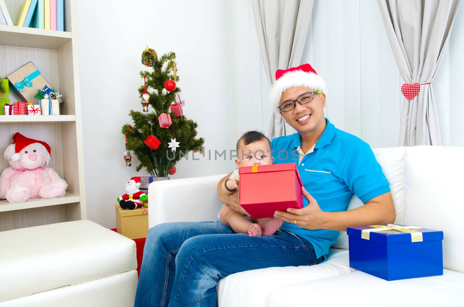 Portrait of happy father and his son in Santa caps on Christmas eve