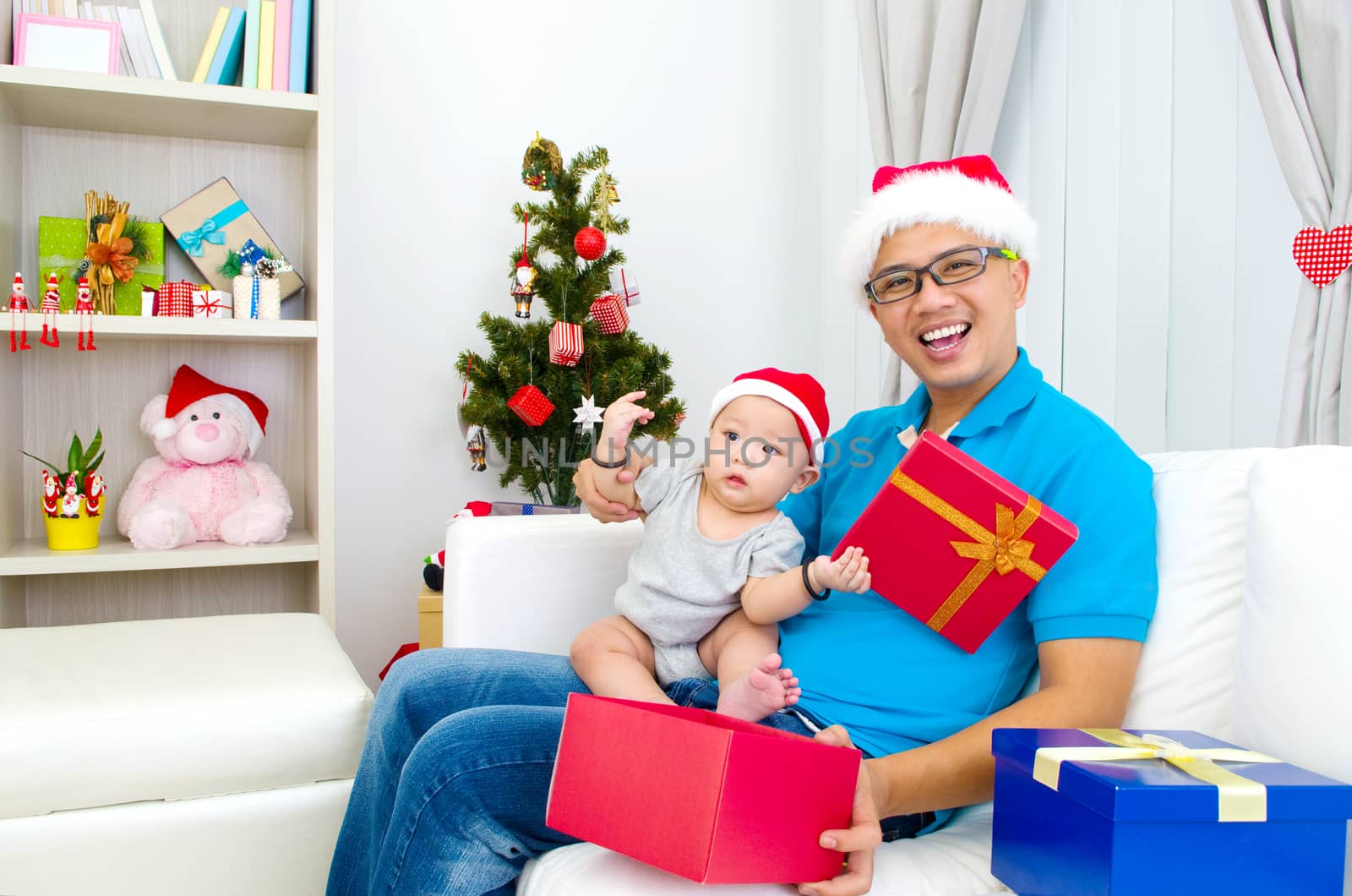 Portrait of happy father and his son in Santa caps on Christmas eve